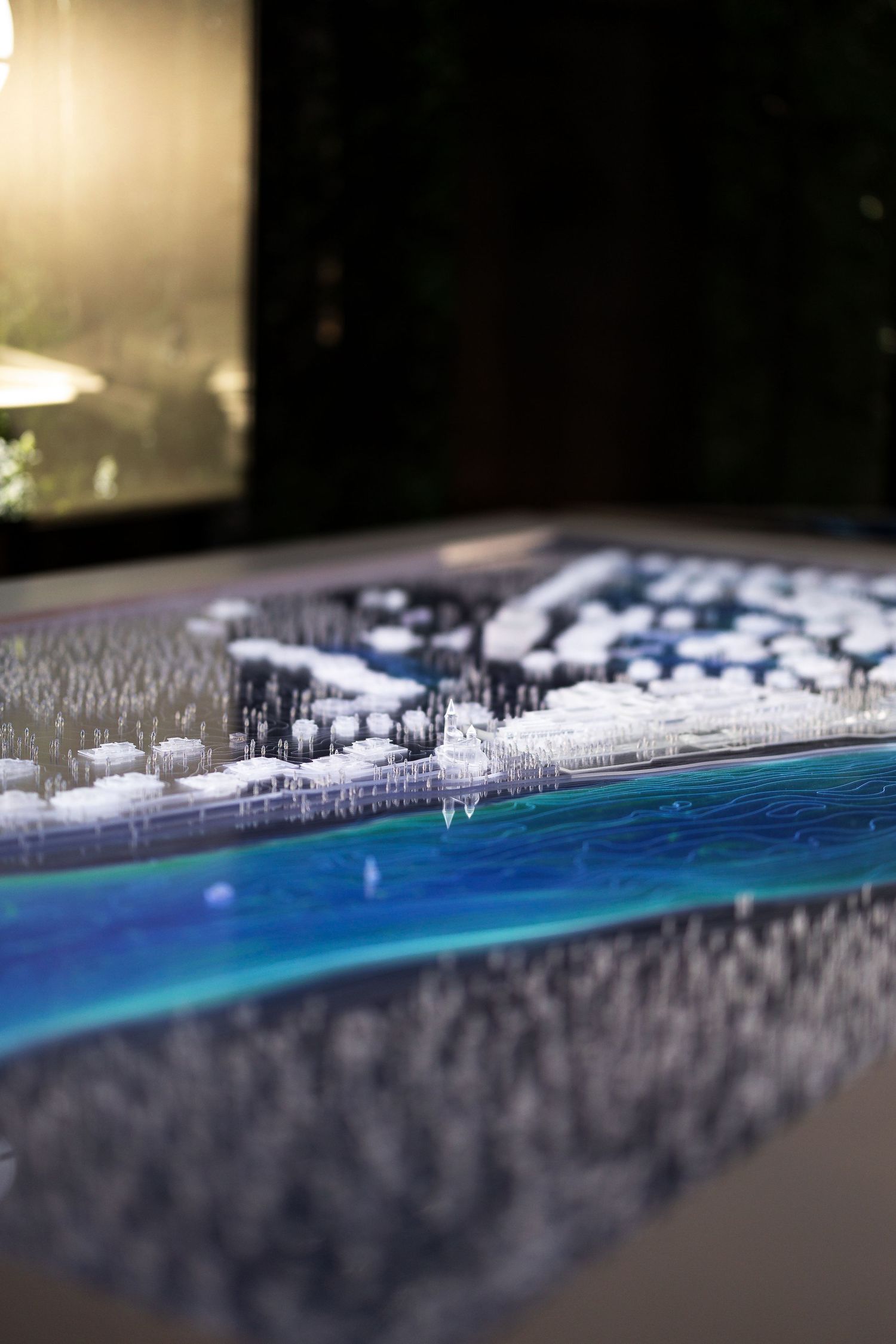 A tilt-shift photograph of a coastal scene with blue water and snow-covered buildings creating a miniature effect.