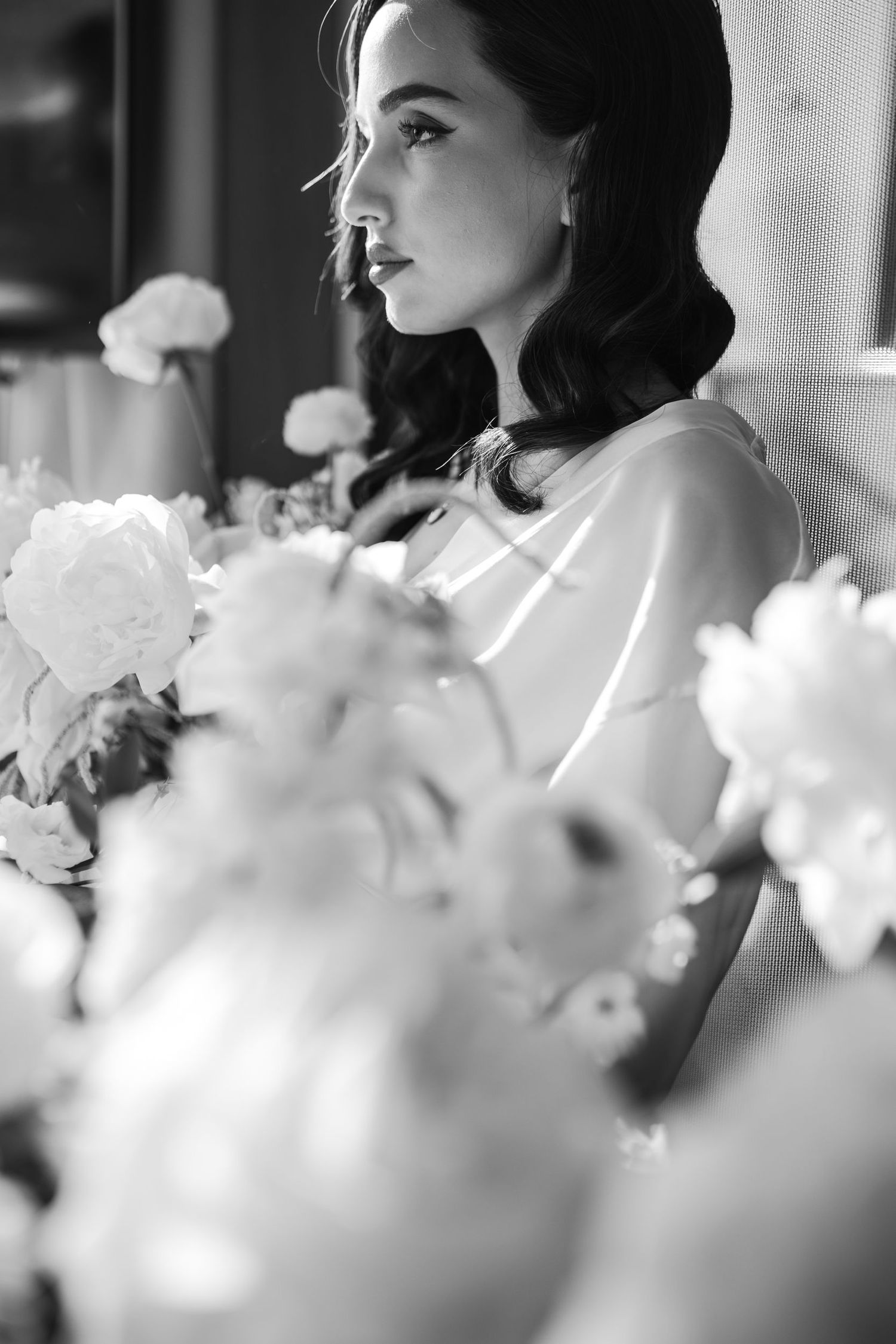 Black and white portrait with soft focus white flowers in foreground.