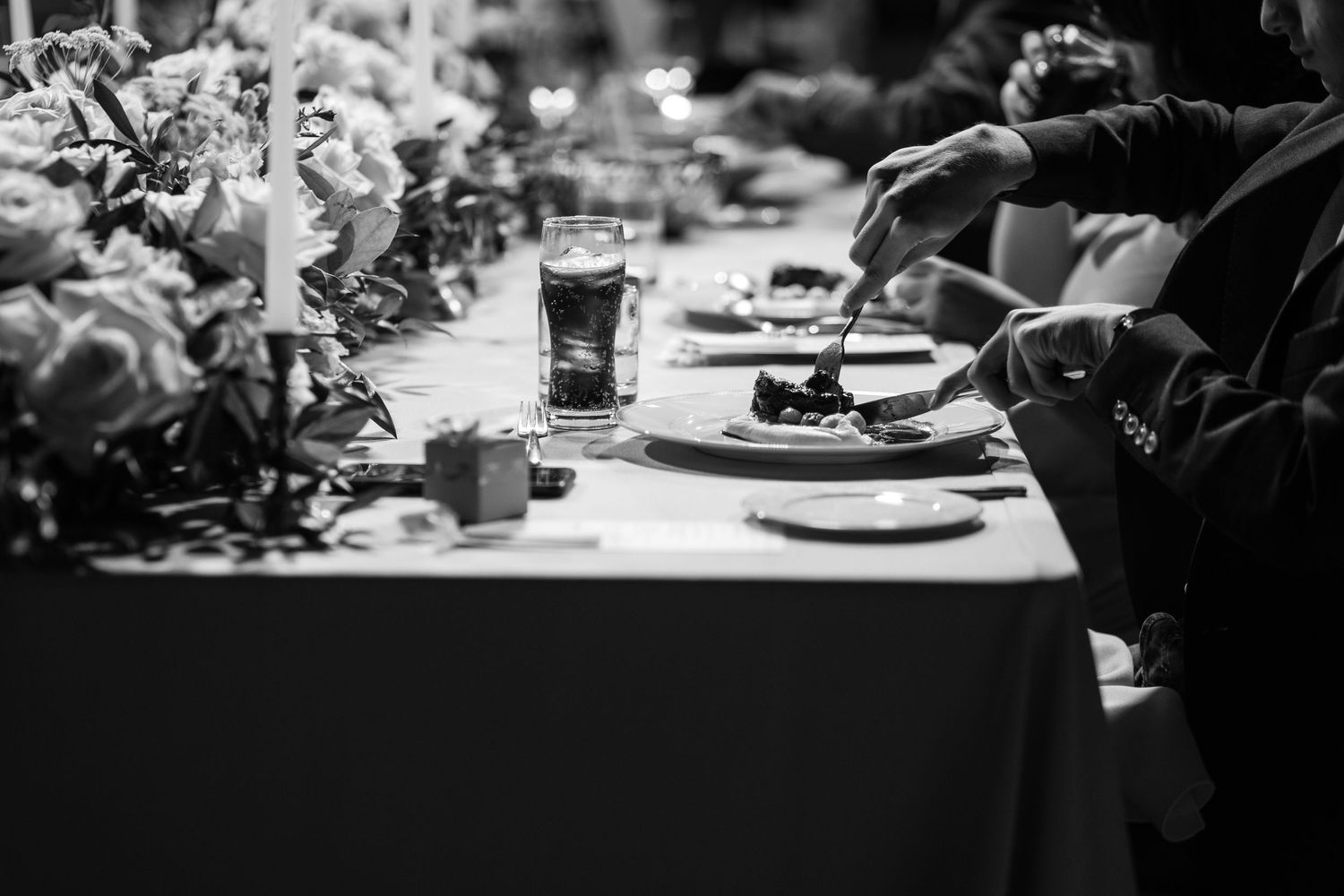 Black and white detail of wedding reception table with candles and place settings.
