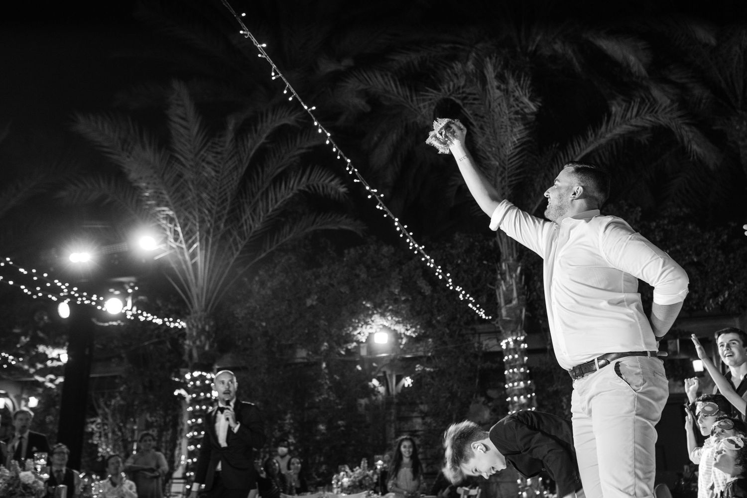 String lights create magical ambiance at nighttime outdoor wedding celebration.
