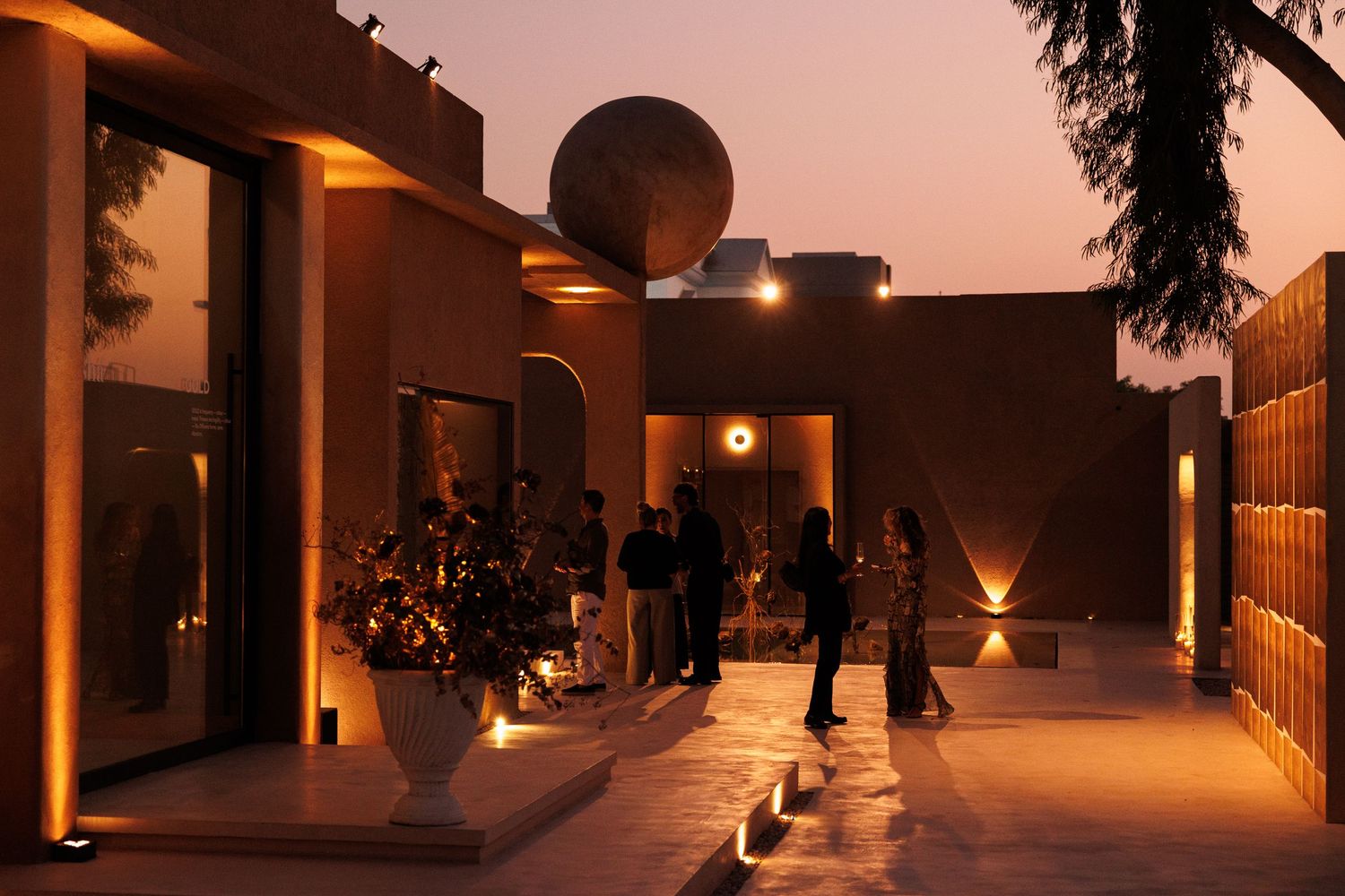 Warm-toned hallway with architectural lighting and silhouetted figures at sunset.