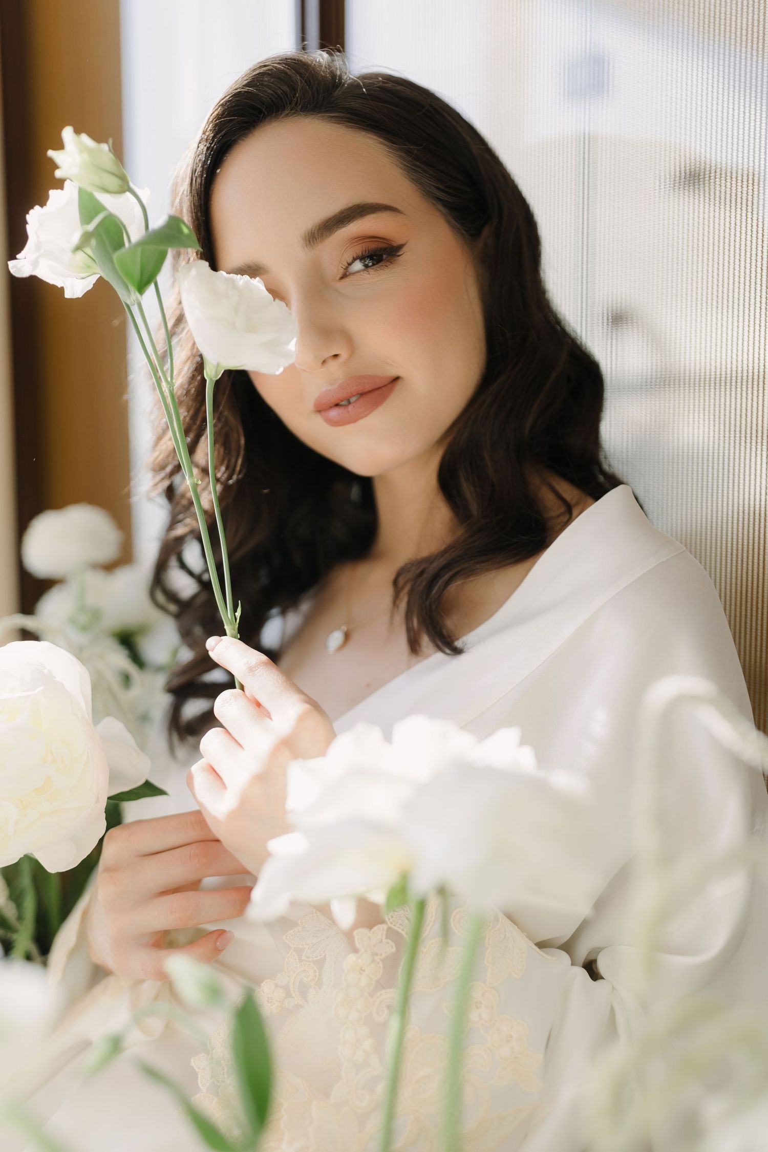 Soft portrait with white roses and gentle window lighting creating romantic atmosphere.