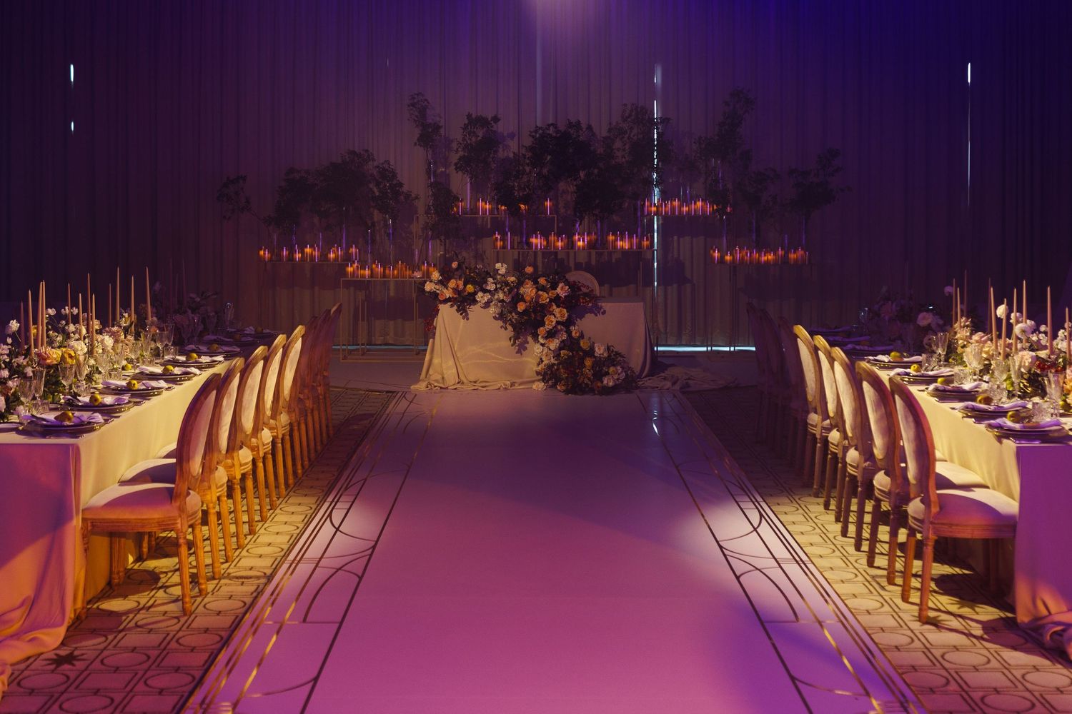 Wedding reception venue with dramatic purple lighting and elegant table settings.