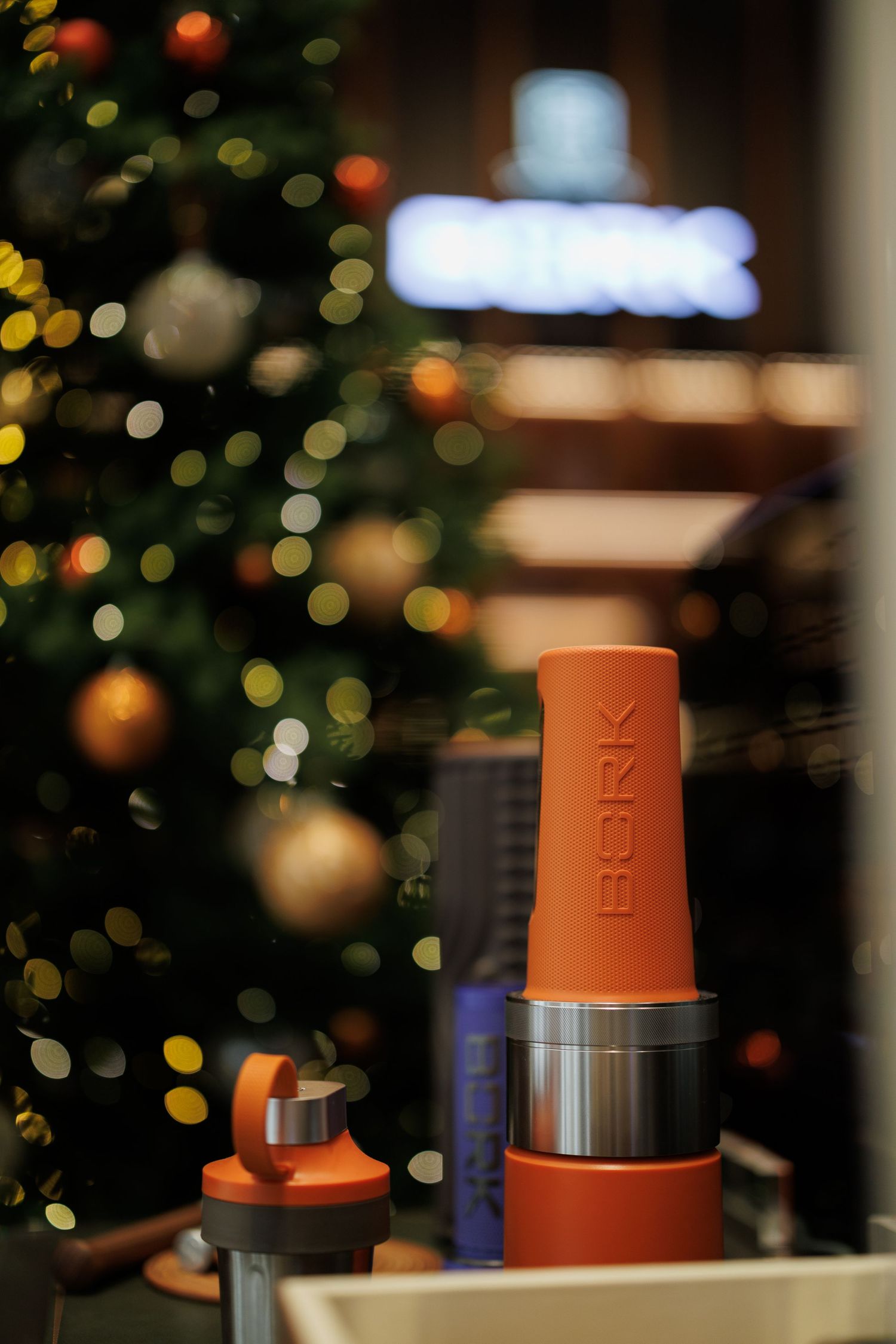 Orange and black drink containers with bokeh lights in the background.