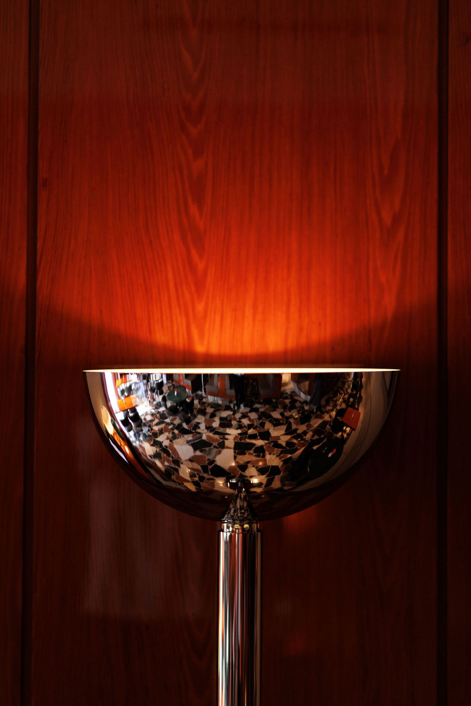 Close-up of illuminated wine glasses against a warm wooden background creating dramatic lighting.