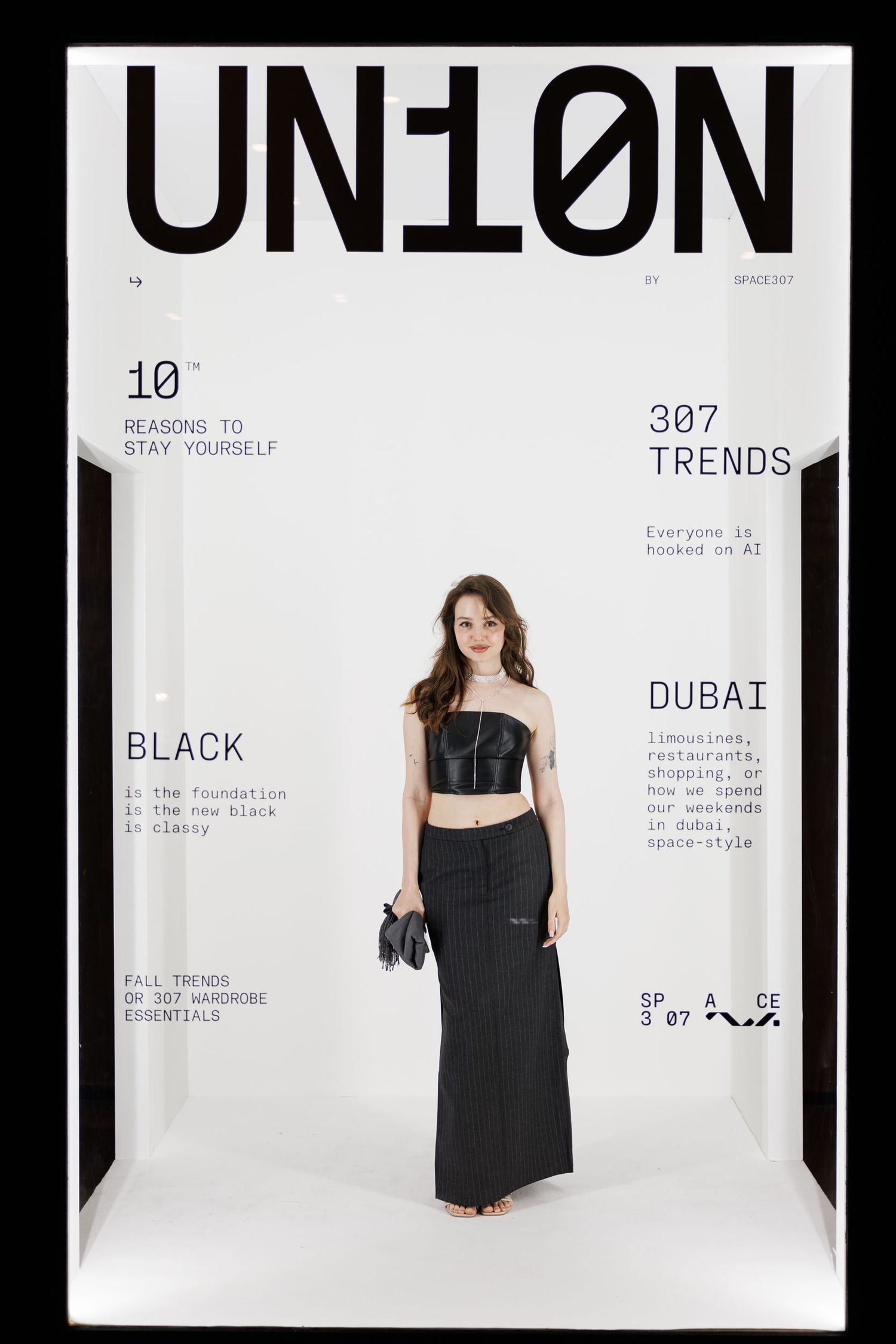 Fashion photo shoot featuring black dress against minimalist white background with text.