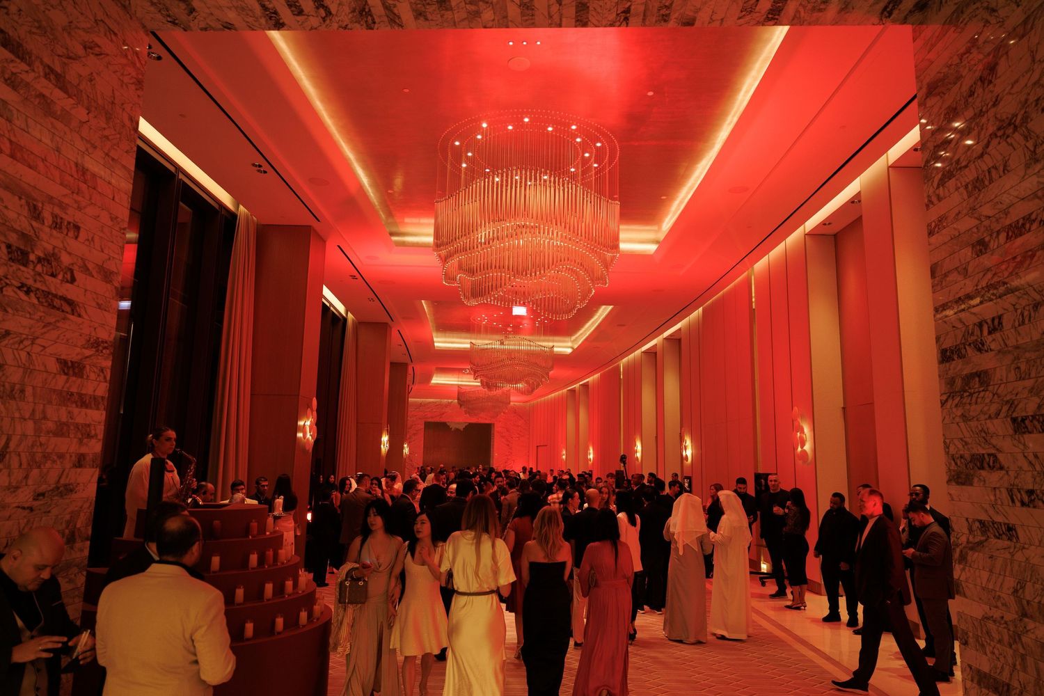 Corporate event venue with red ambient lighting and guests mingling in formal attire.