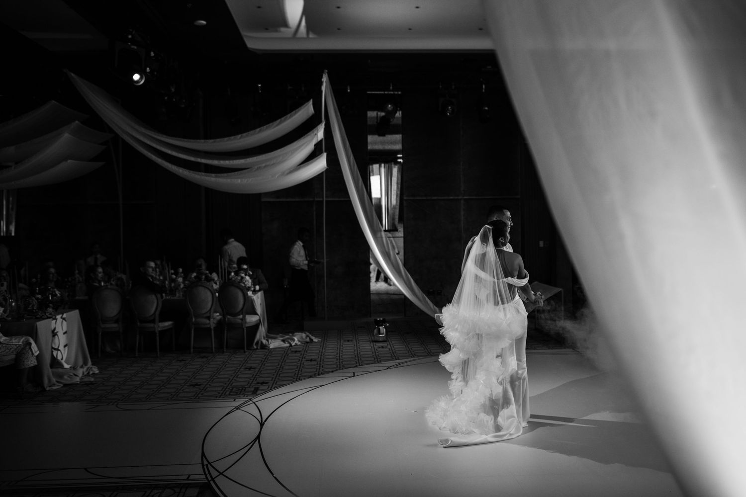 Atmospheric black and white wedding venue photo with dramatic lighting and shadows.