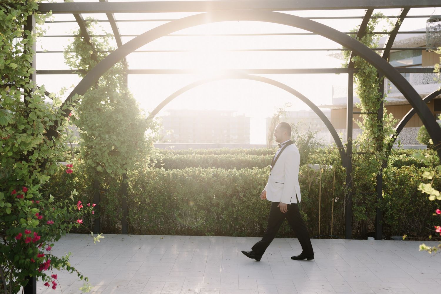 Elegant wedding venue with white arches and lush greenery in golden sunlight.