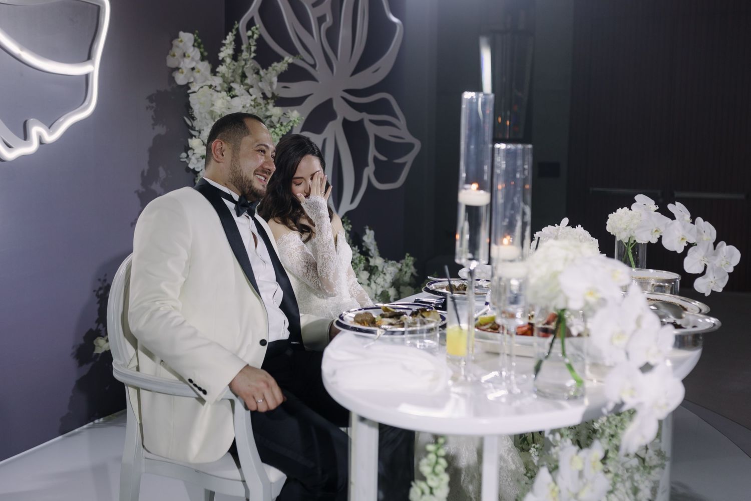 Wedding reception tables decorated with white orchids and elegant place settings.