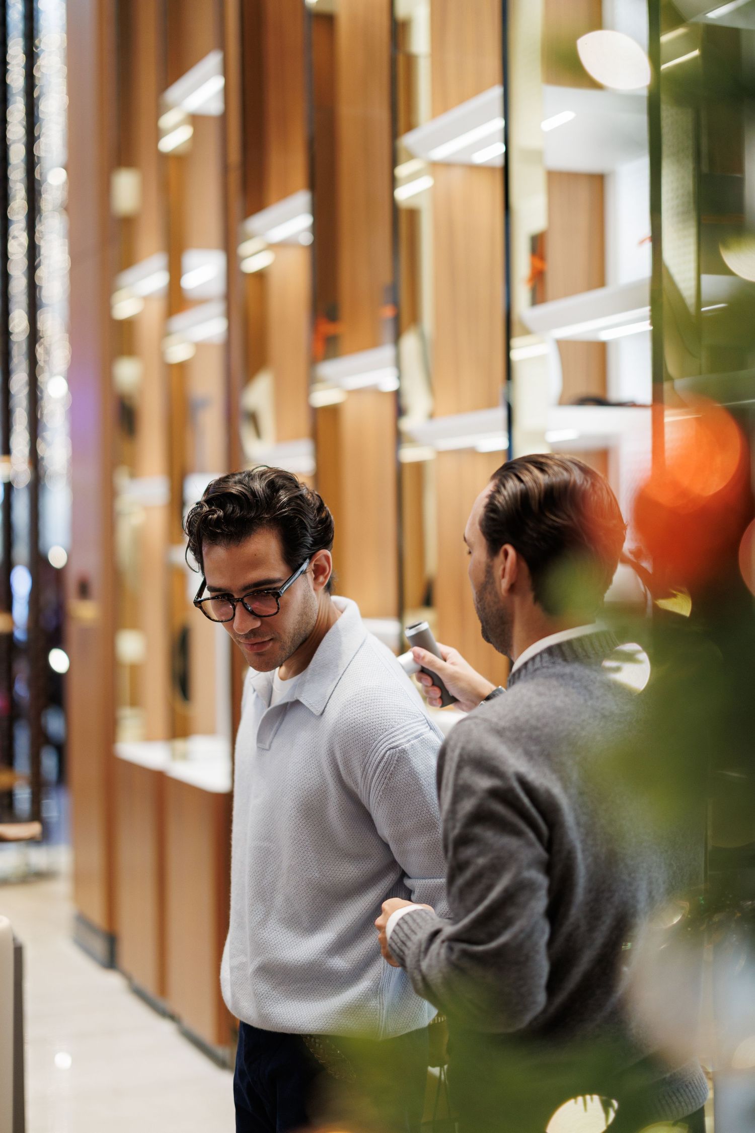 Two people having conversation in modern office hallway with wood paneled walls.