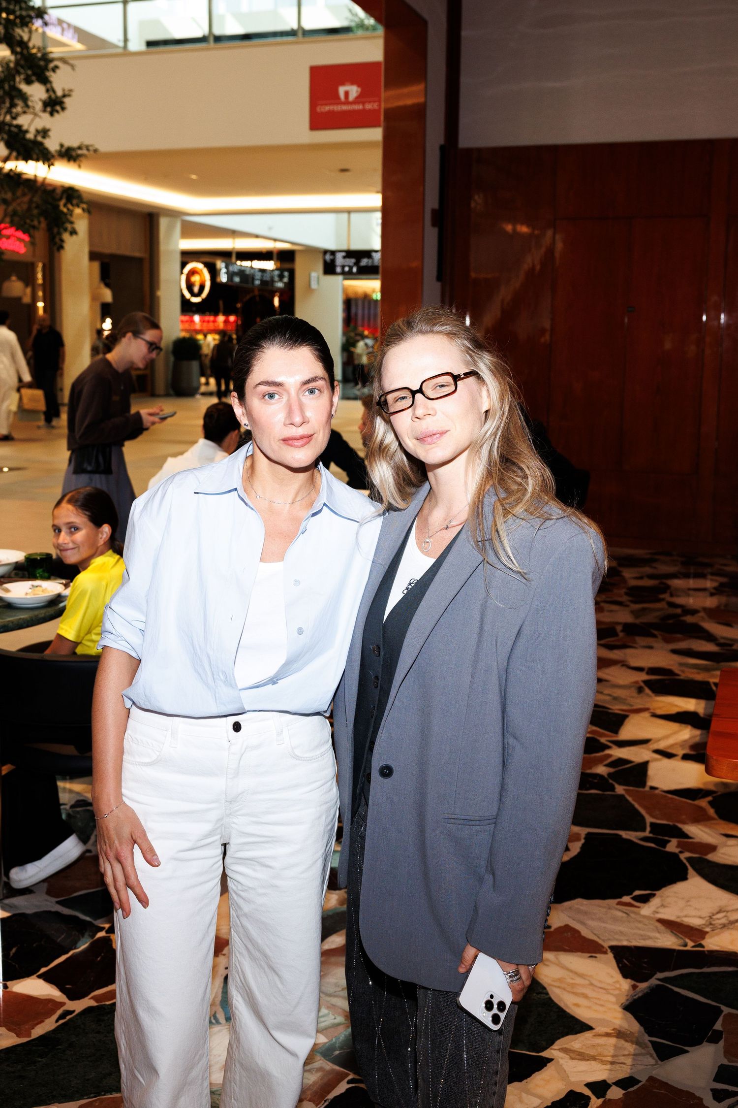 Two people standing in a shopping mall interior with modern decor.
