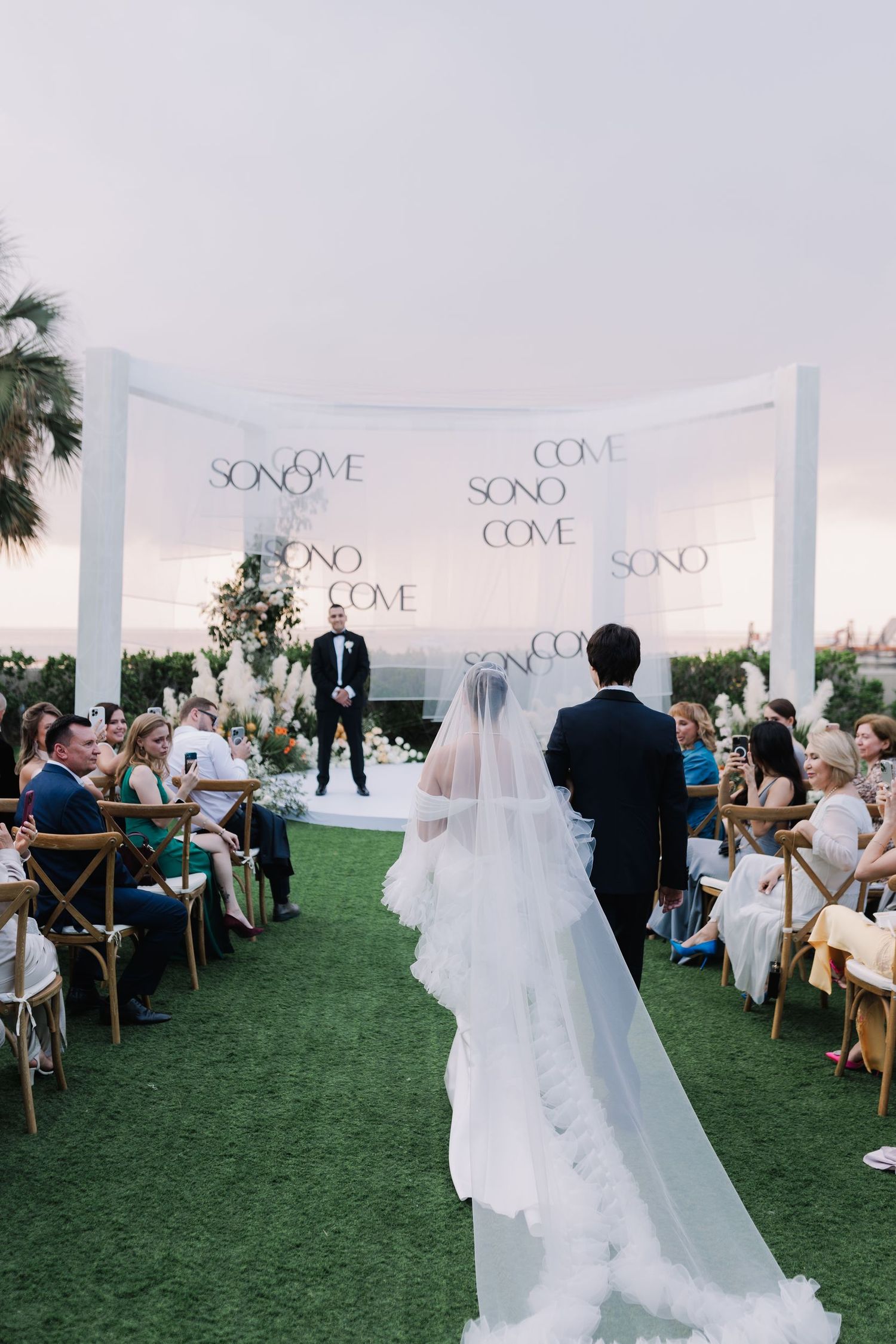 Outdoor wedding ceremony space with white draping and 'SONO' signage on display.