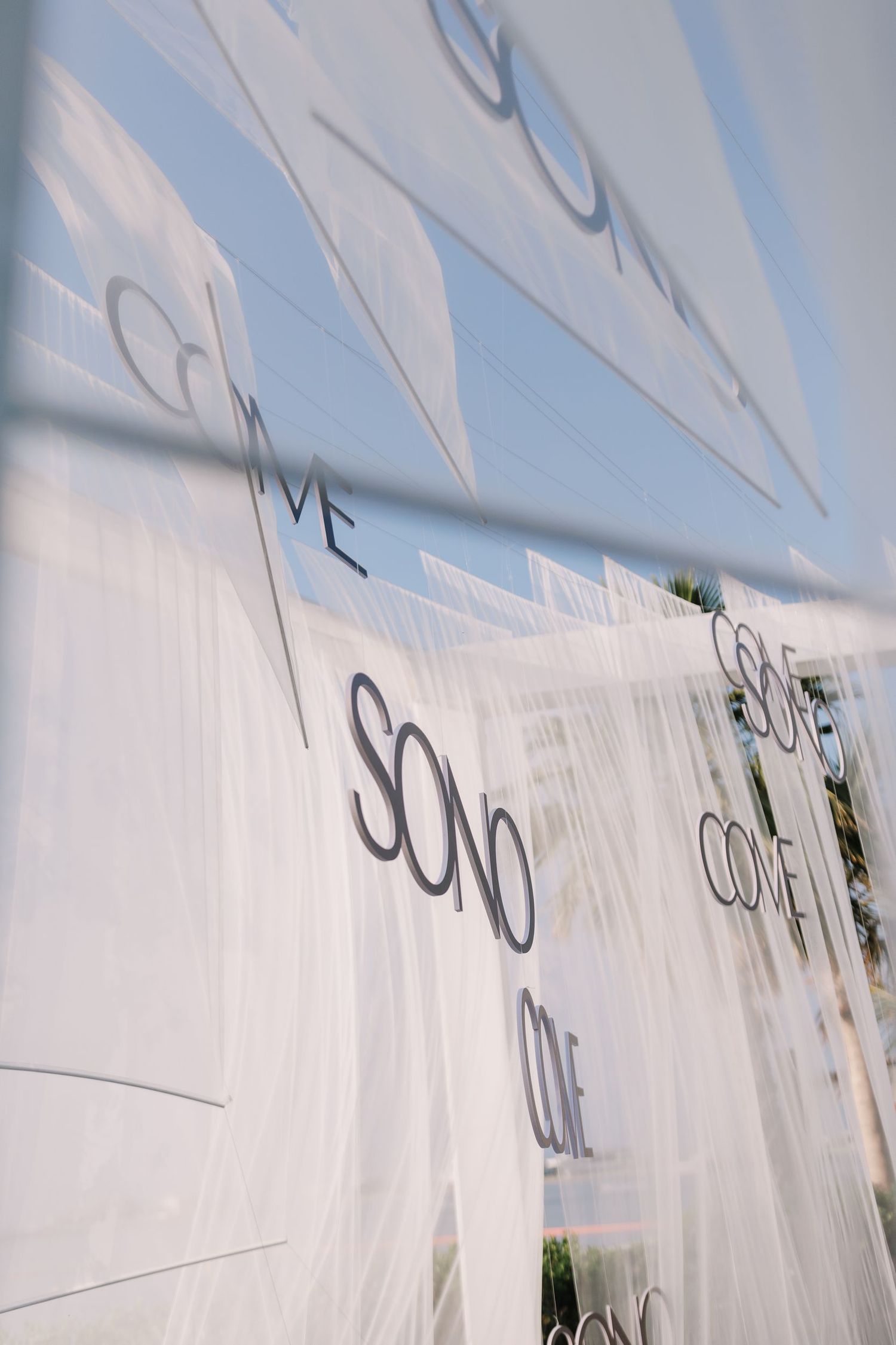 White fabric banners with text flutter in the breeze against a bright blue sky.