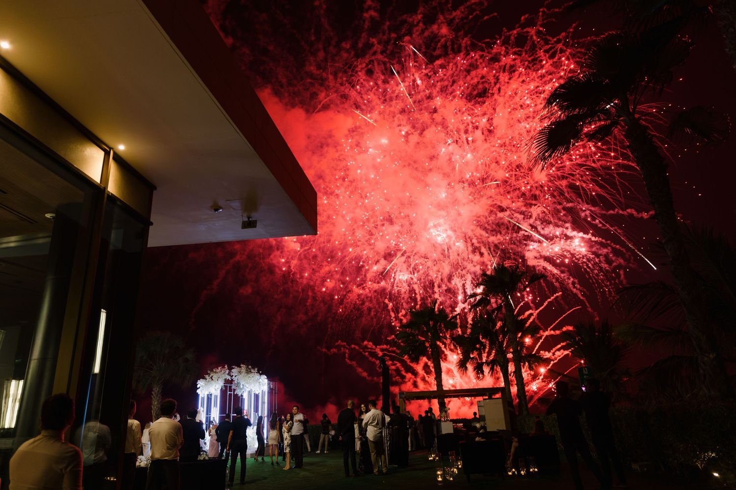 Stunning red fireworks display illuminating the night sky at an outdoor celebration.