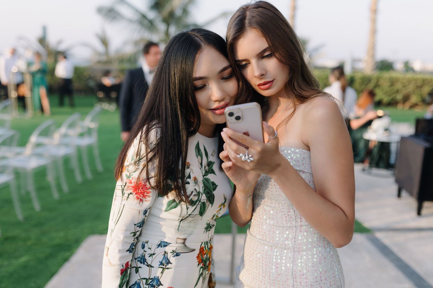 Two guests looking at a phone together at an outdoor wedding reception.
