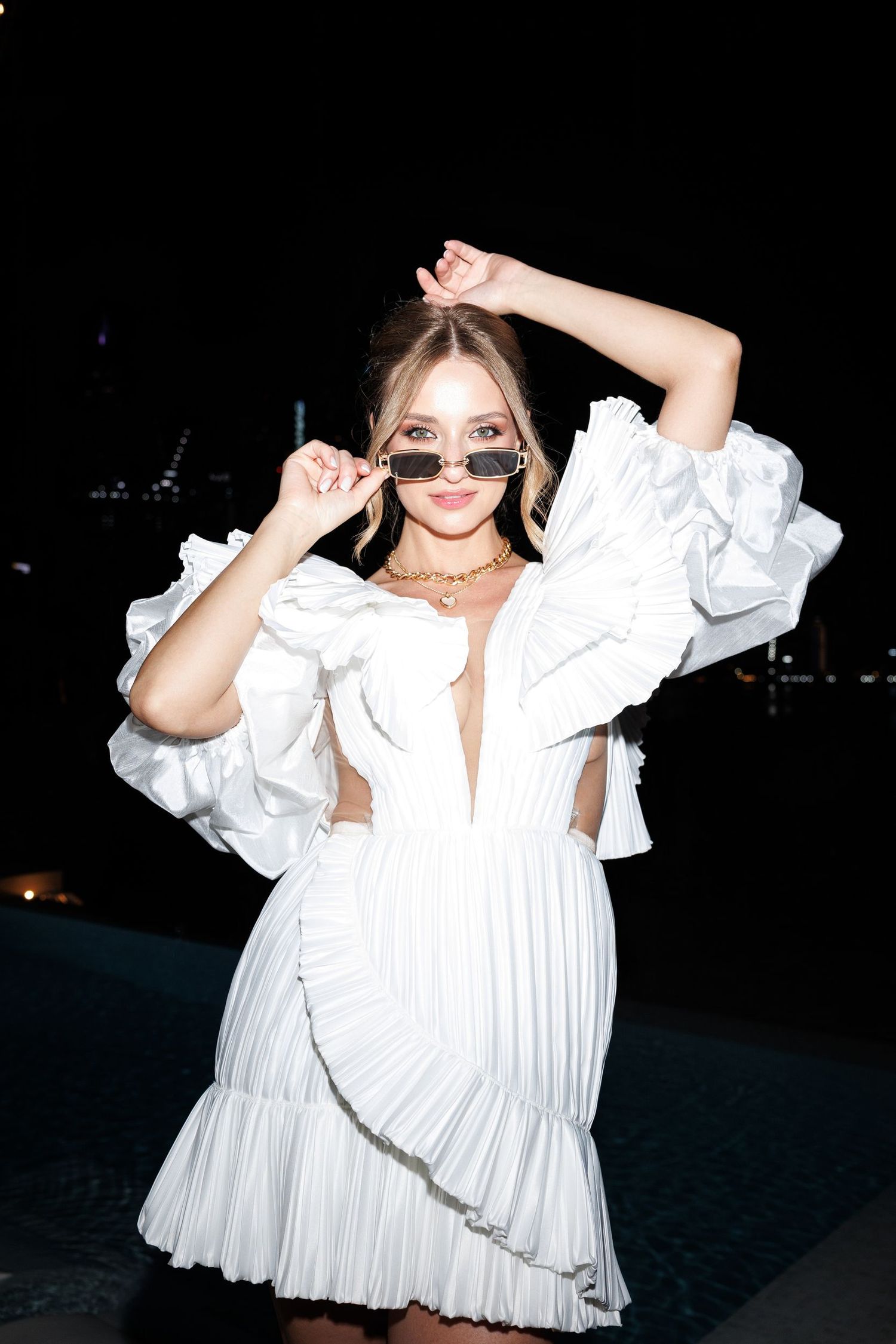 Playful nighttime portrait in a white pleated mini dress.