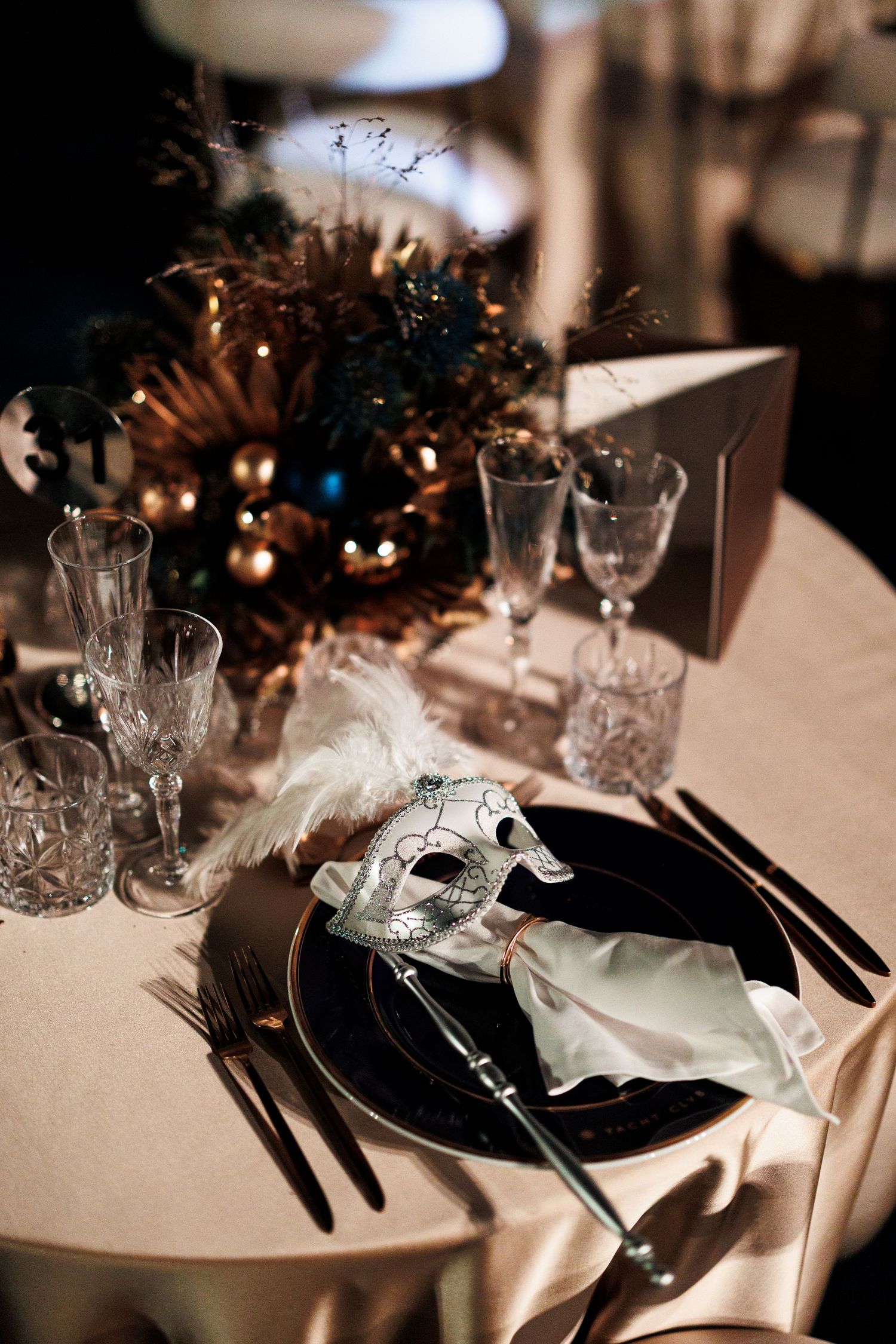 Elegant place settings with crystal glasses and black plates on white tablecloths create a sophisticated dining atmosphere.