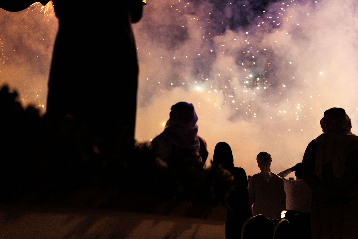 Silhouettes of riders on camels against a dusky purple sky with twinkling lights creating a mystical atmosphere.