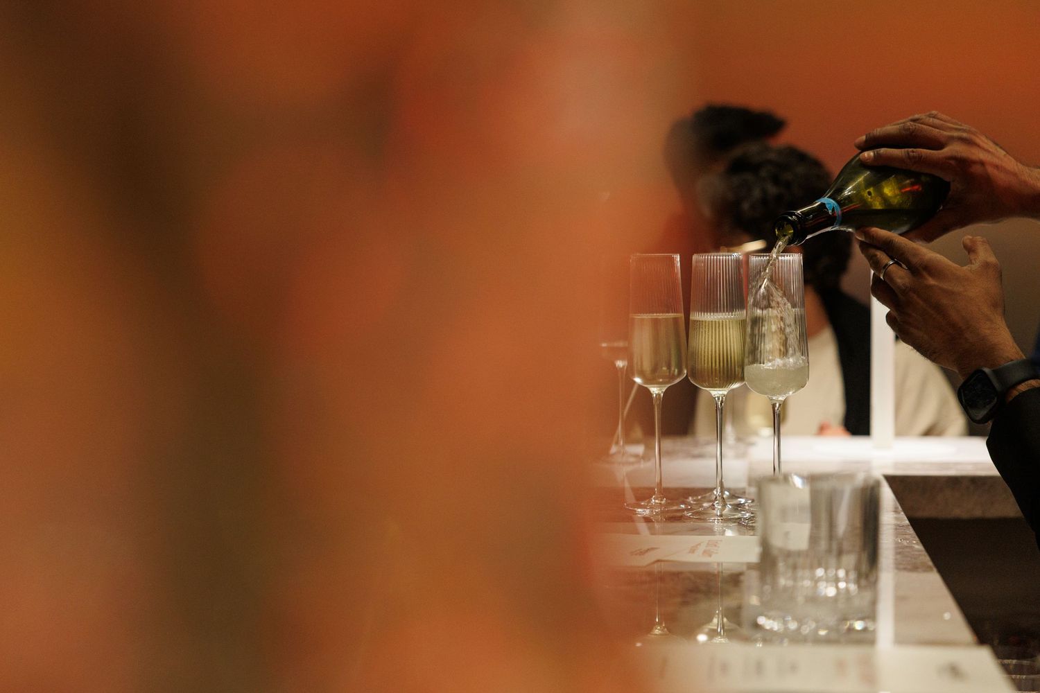 Blurred close-up of wine glasses on table with warm ambient lighting.