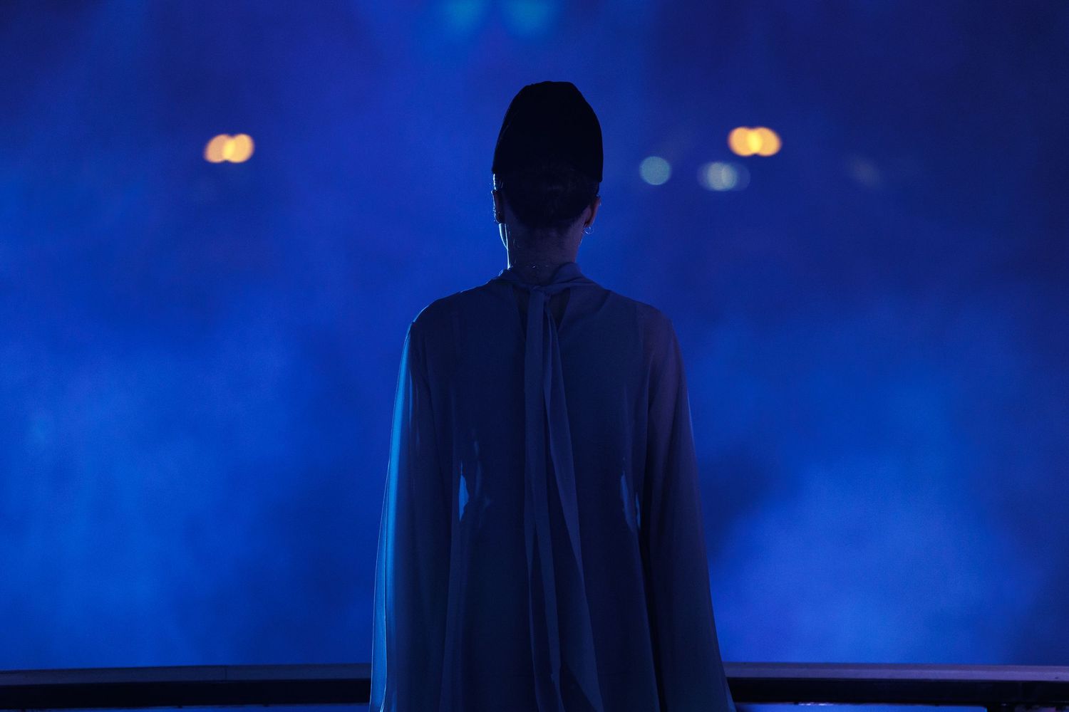 Silhouette against deep blue stage lighting creating a dramatic atmospheric effect.