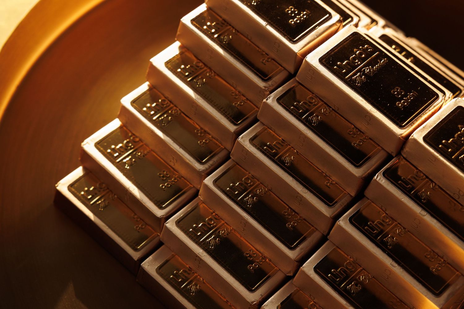Metallic gold rectangles arranged in rows with dramatic lighting and reflective surfaces.