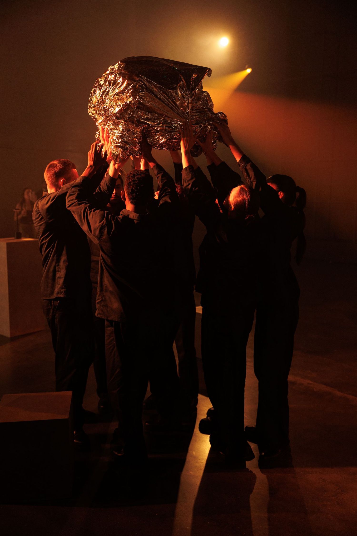Line of people standing in dramatic amber lighting creating mysterious silhouettes.