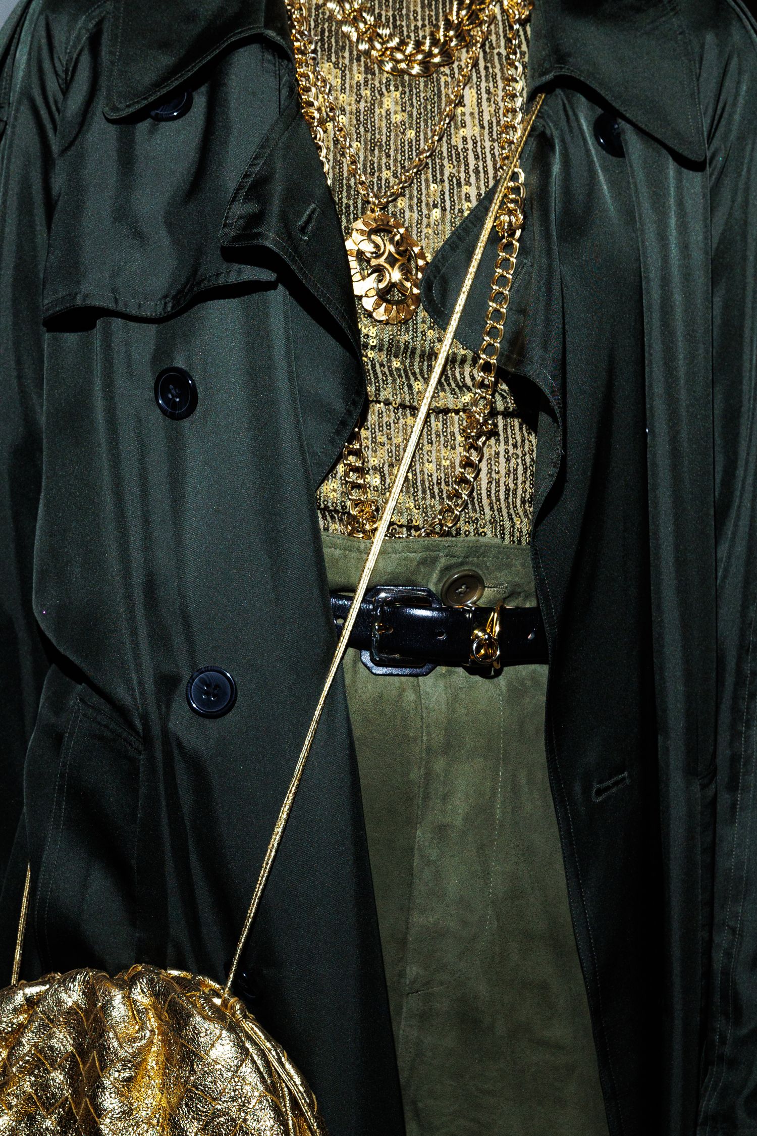 Close-up of black coats and gold metallic accessories against a dark background.