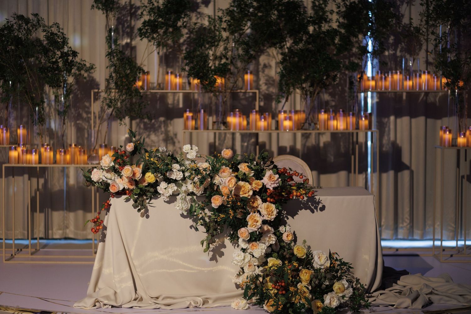 Elegant wedding reception table with hanging candles and floral arrangements.