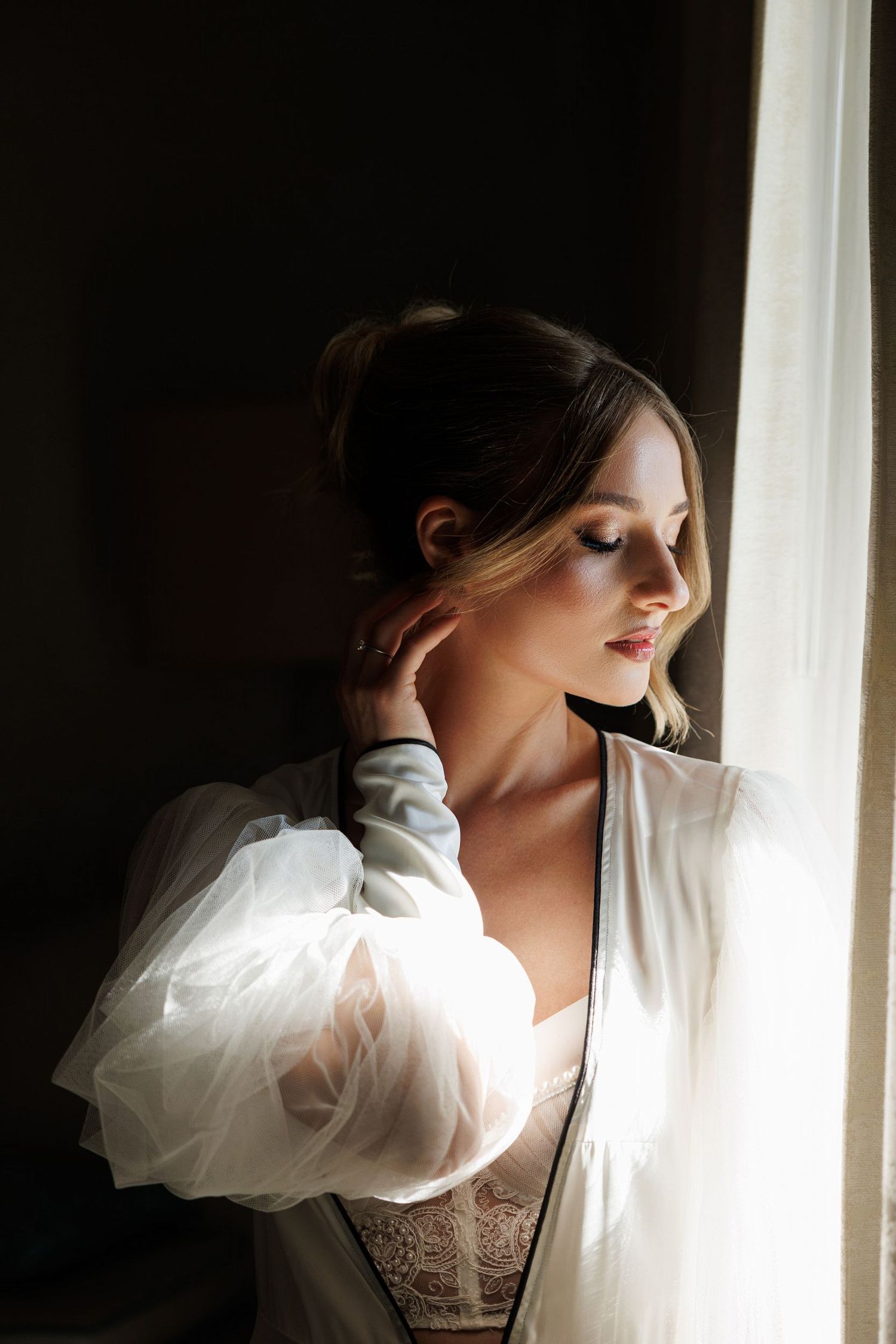 Dramatic silhouette against window light in flowing white robe.