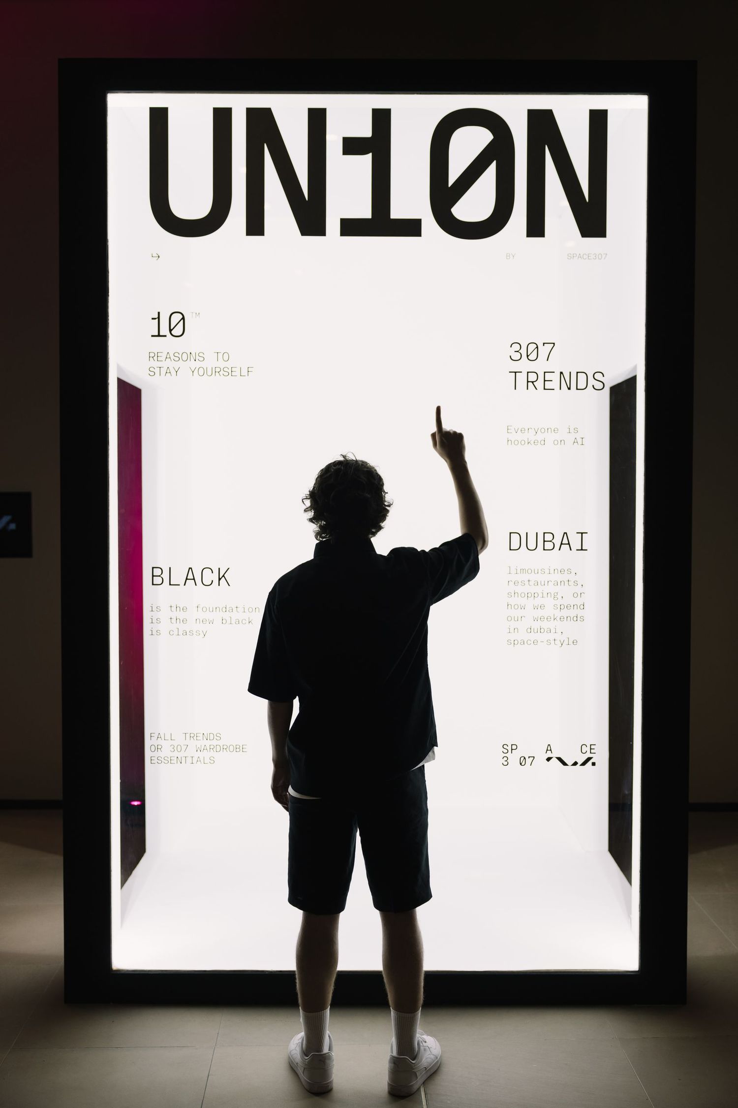 Artistic silhouettes of figures posed against bright white exhibition panels.