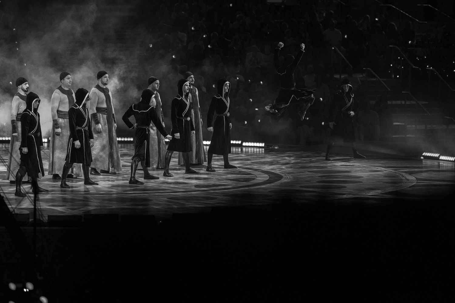 Dancers performing on a dimly lit stage with dramatic spotlighting effects.
