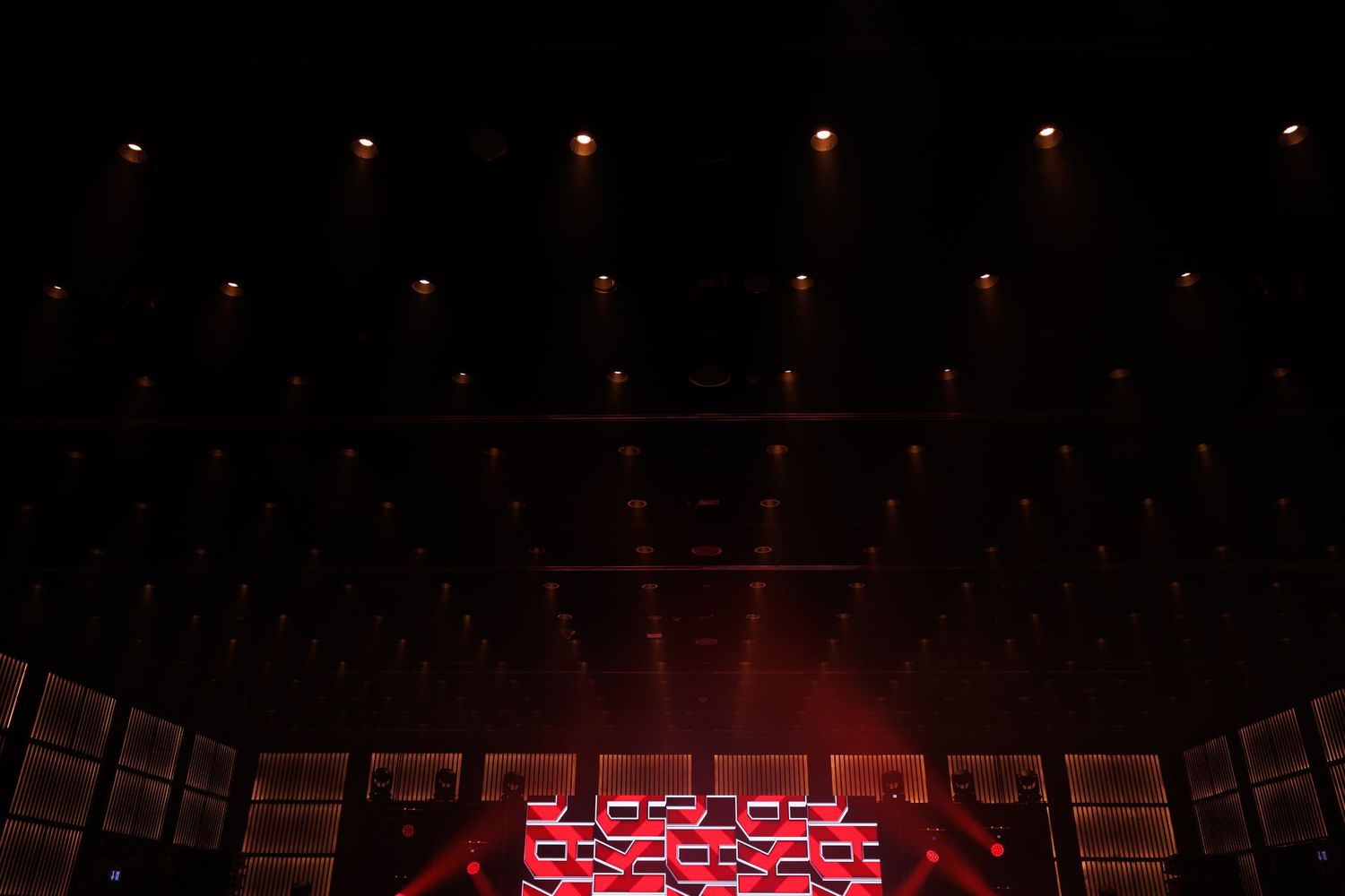 Stage lighting grid with red illumination creates dramatic atmosphere.