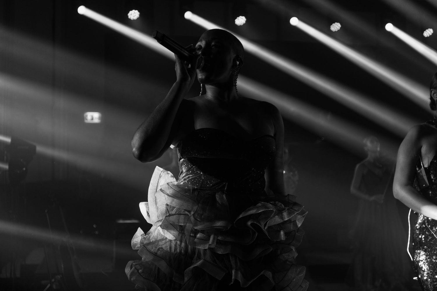 Dramatic black and white stage lighting with parallel beams cutting through darkness.