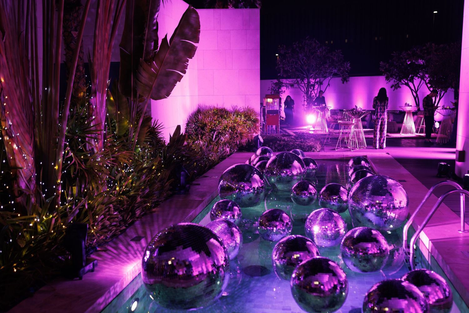 Purple-lit outdoor party space with disco balls and ambient lighting creating a festive atmosphere.