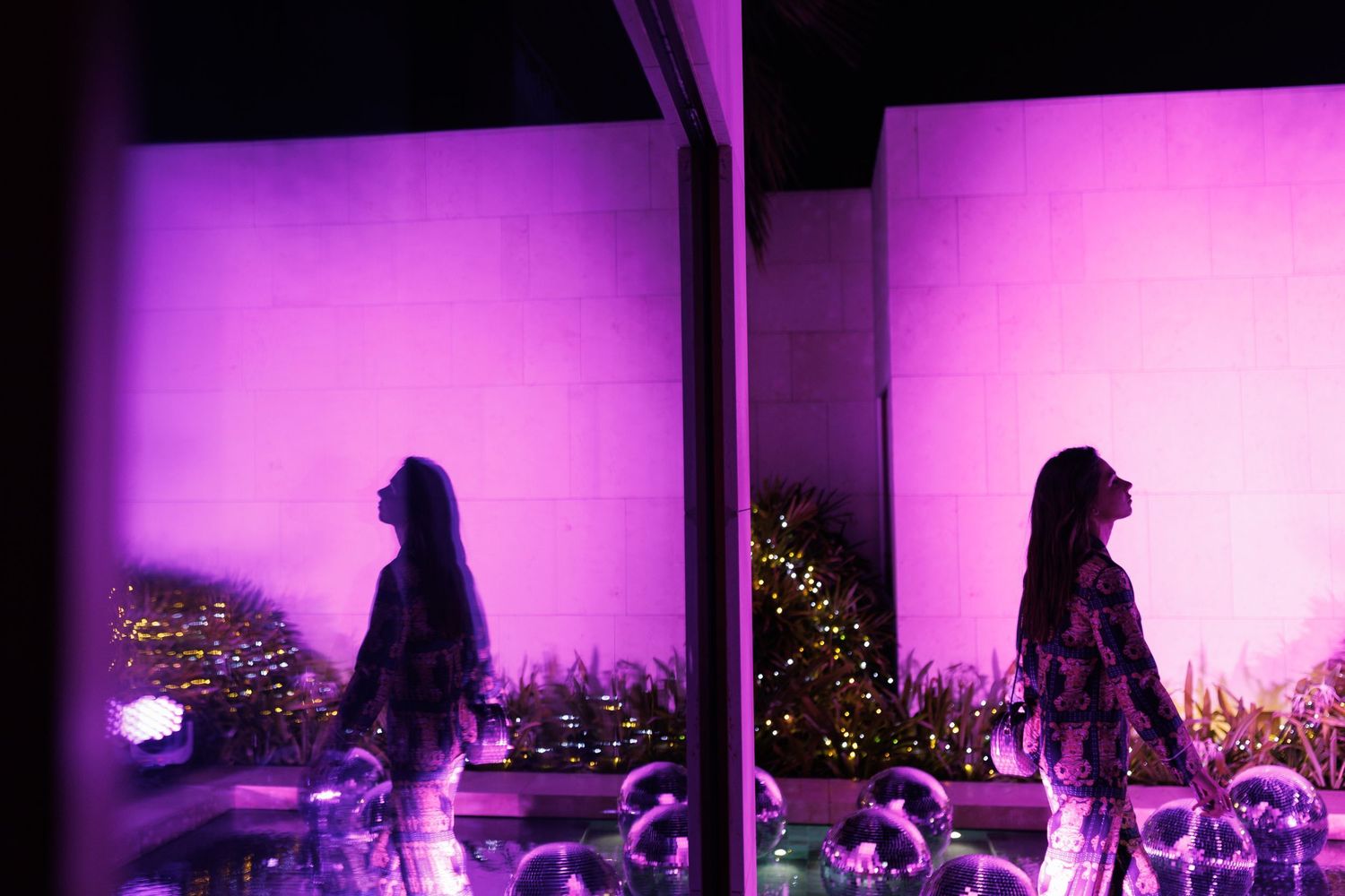 Silhouettes against a vibrant purple-lit backdrop at an outdoor event.