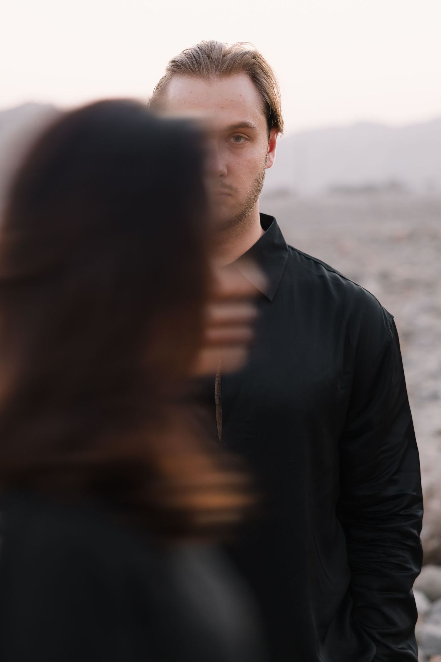 Artistic portrait with selective focus and blurred elements against natural backdrop.
