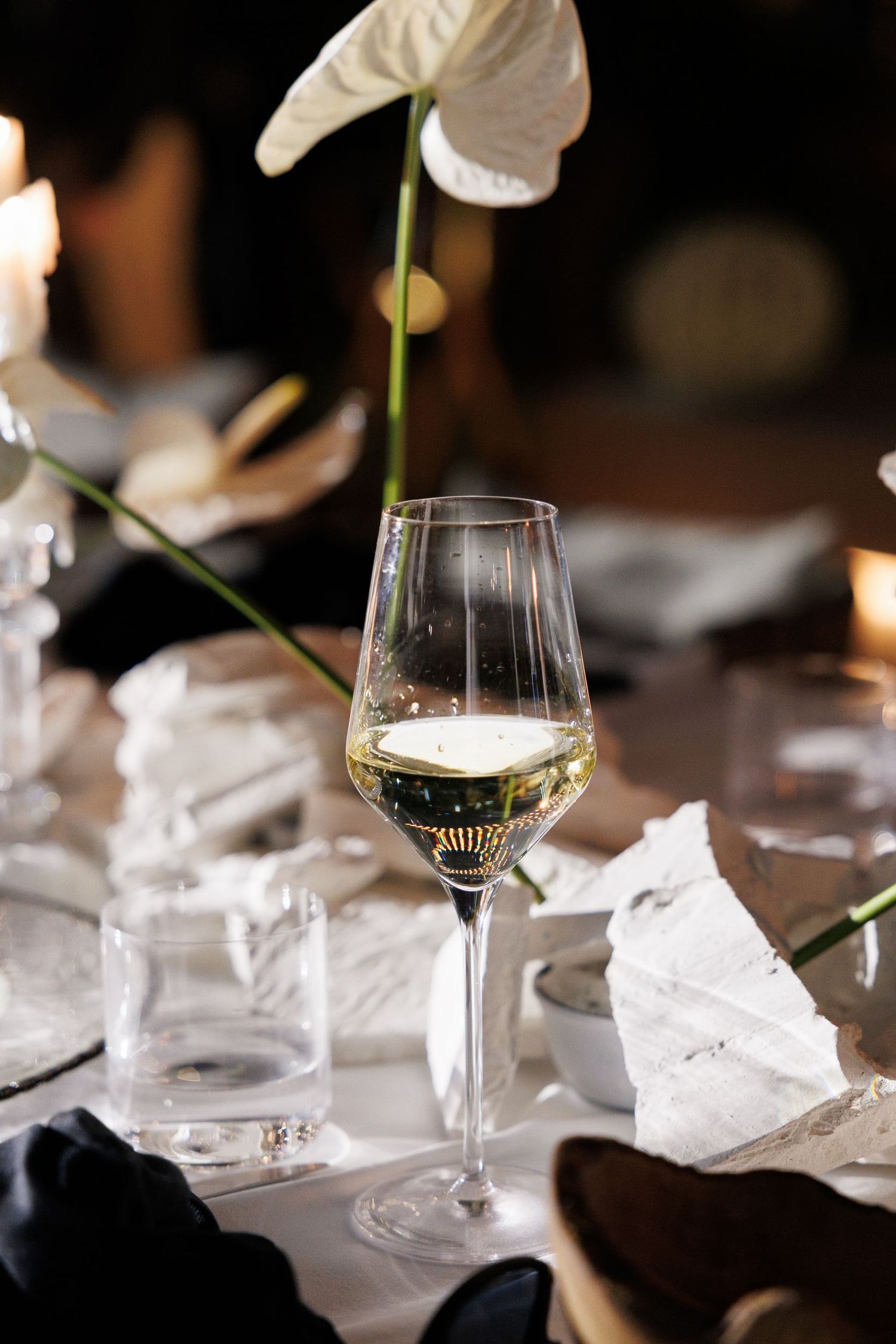 Elegant table setting with wine glasses and white floral decorations.