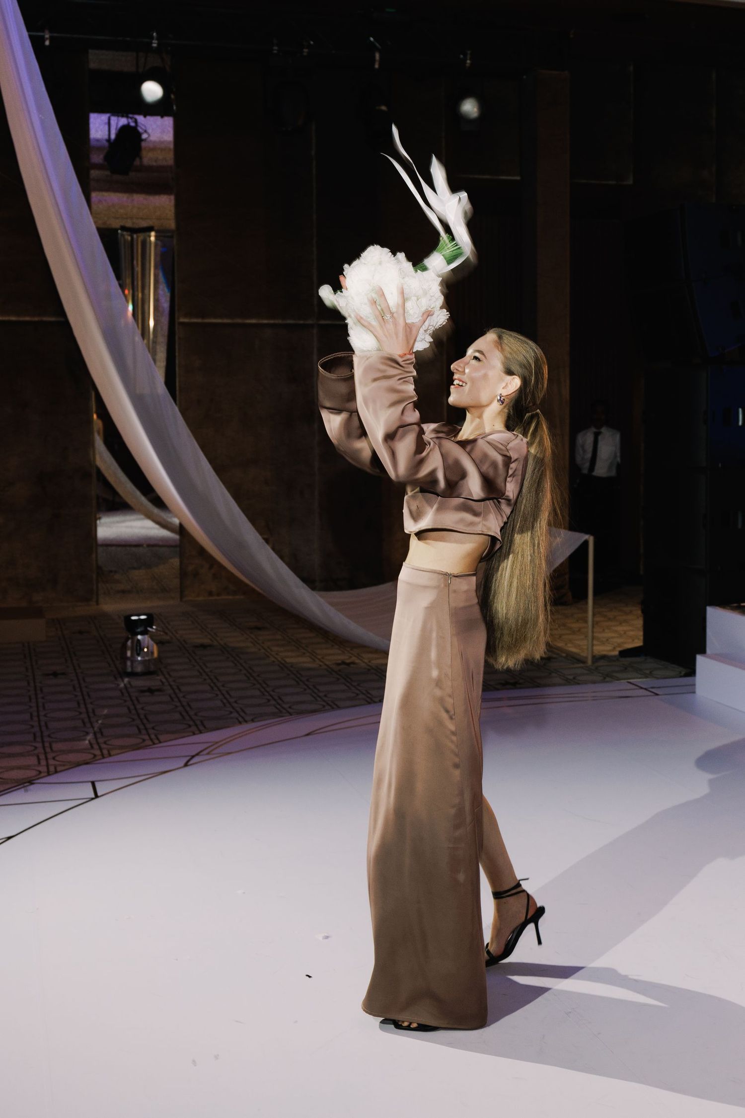 Performance on white stage with flowing fabric decor and dramatic lighting.