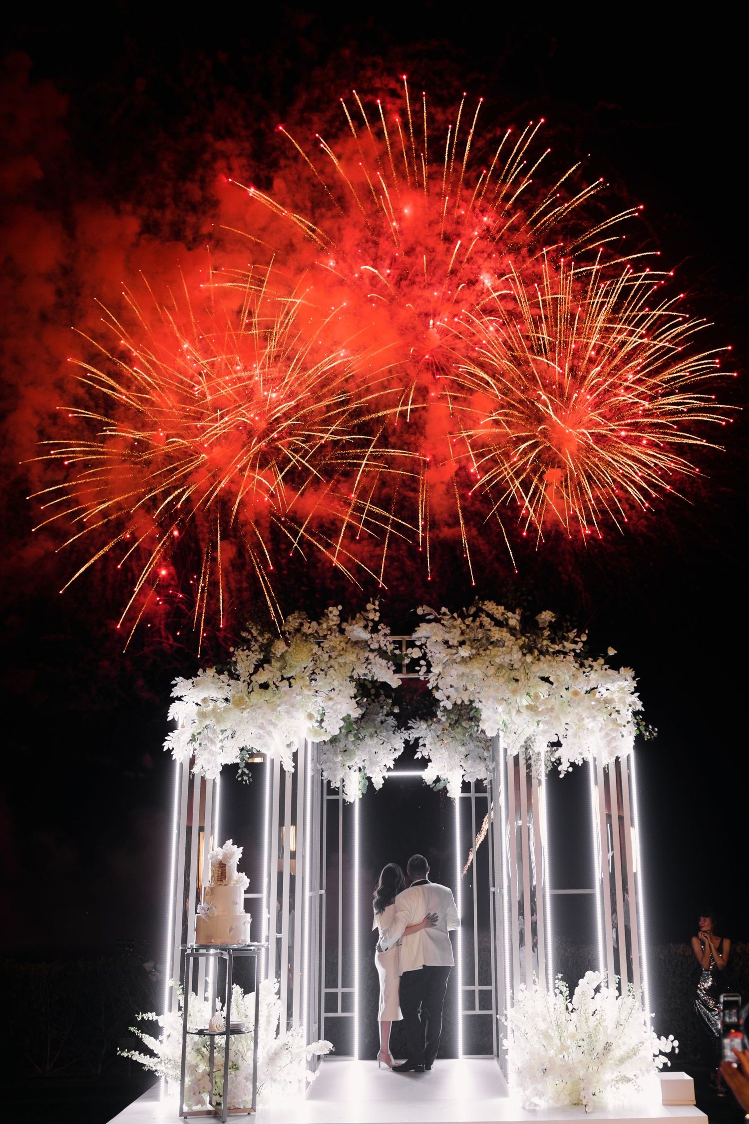 Illuminated wedding ceremony setup with red fireworks display creating a magical atmosphere.