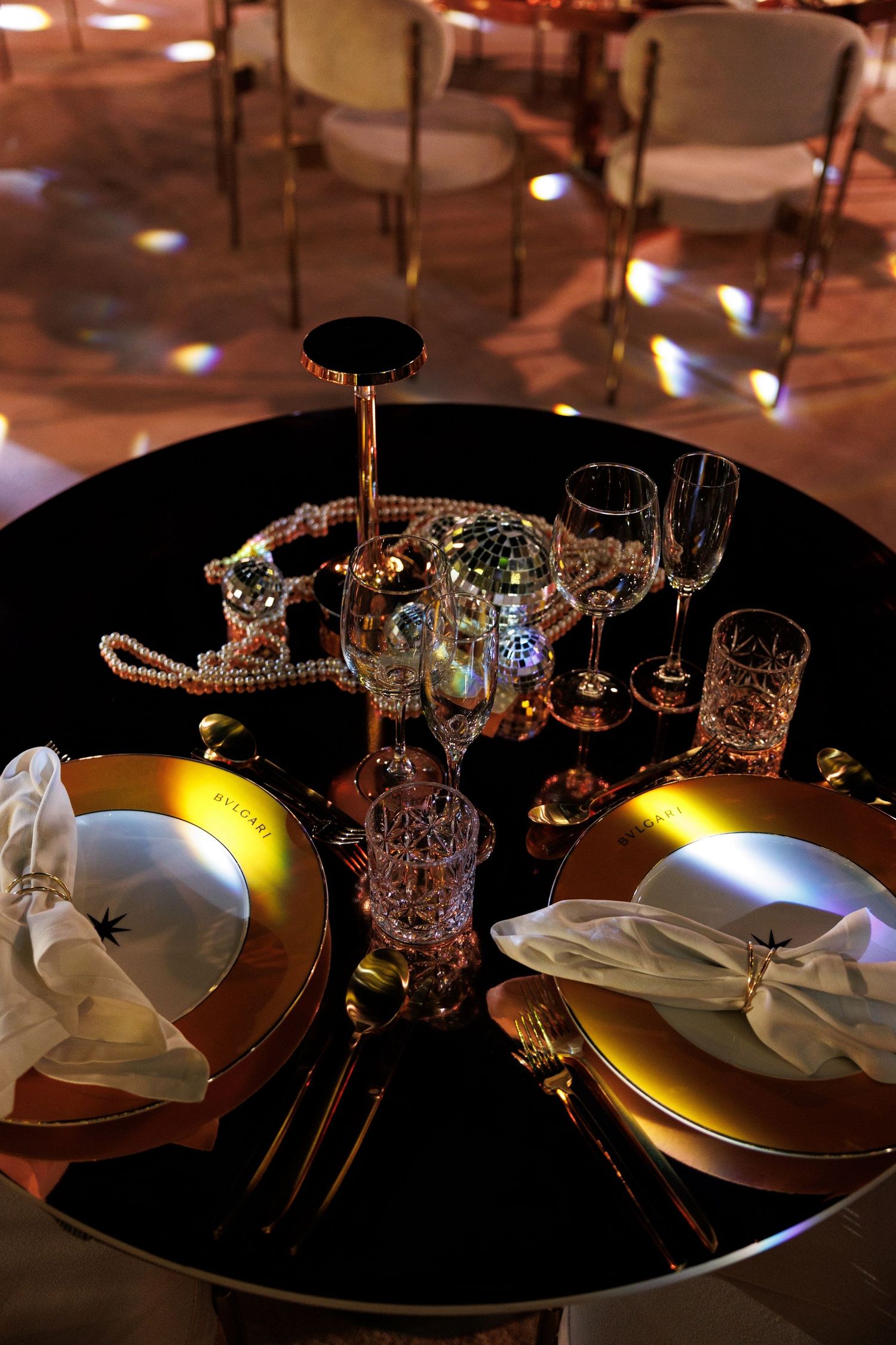 Luxurious table setting with crystal glassware and white napkins on gold-rimmed plates.