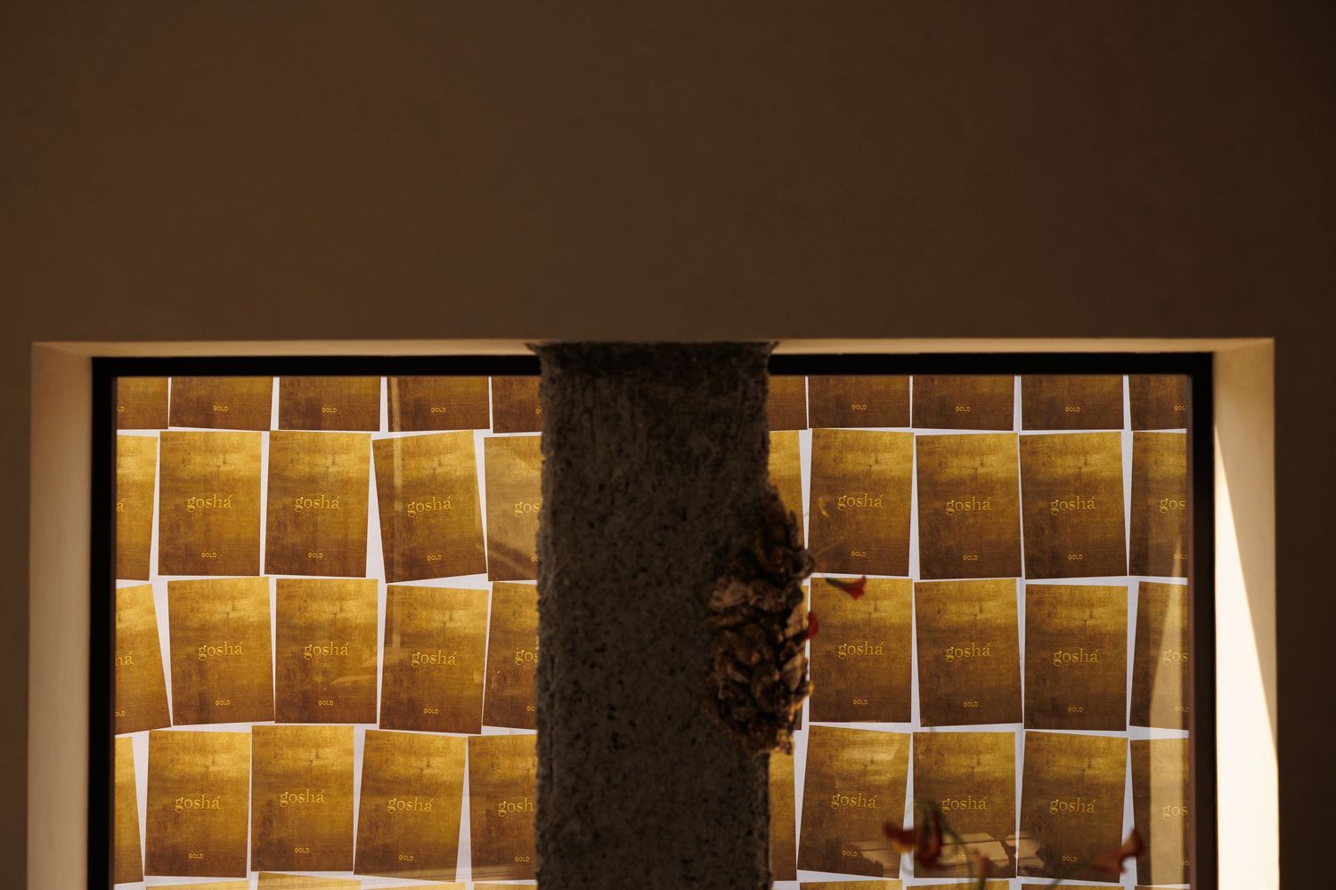 Illuminated display wall with golden squares arranged in a grid pattern behind glass.