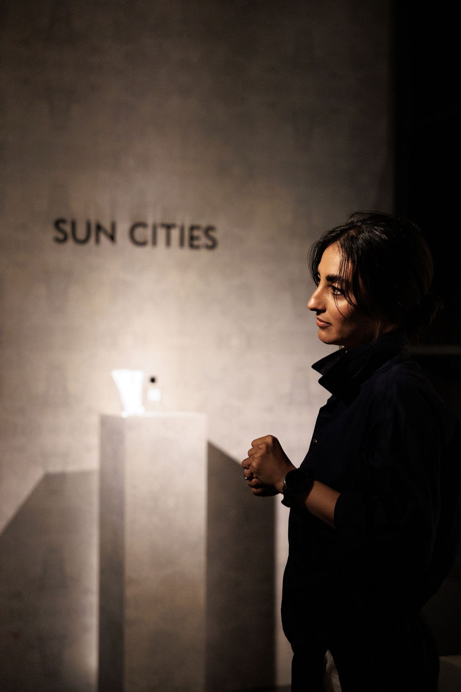 Silhouetted figure against a wall with 'Sun Cities' text visible in moody lighting.