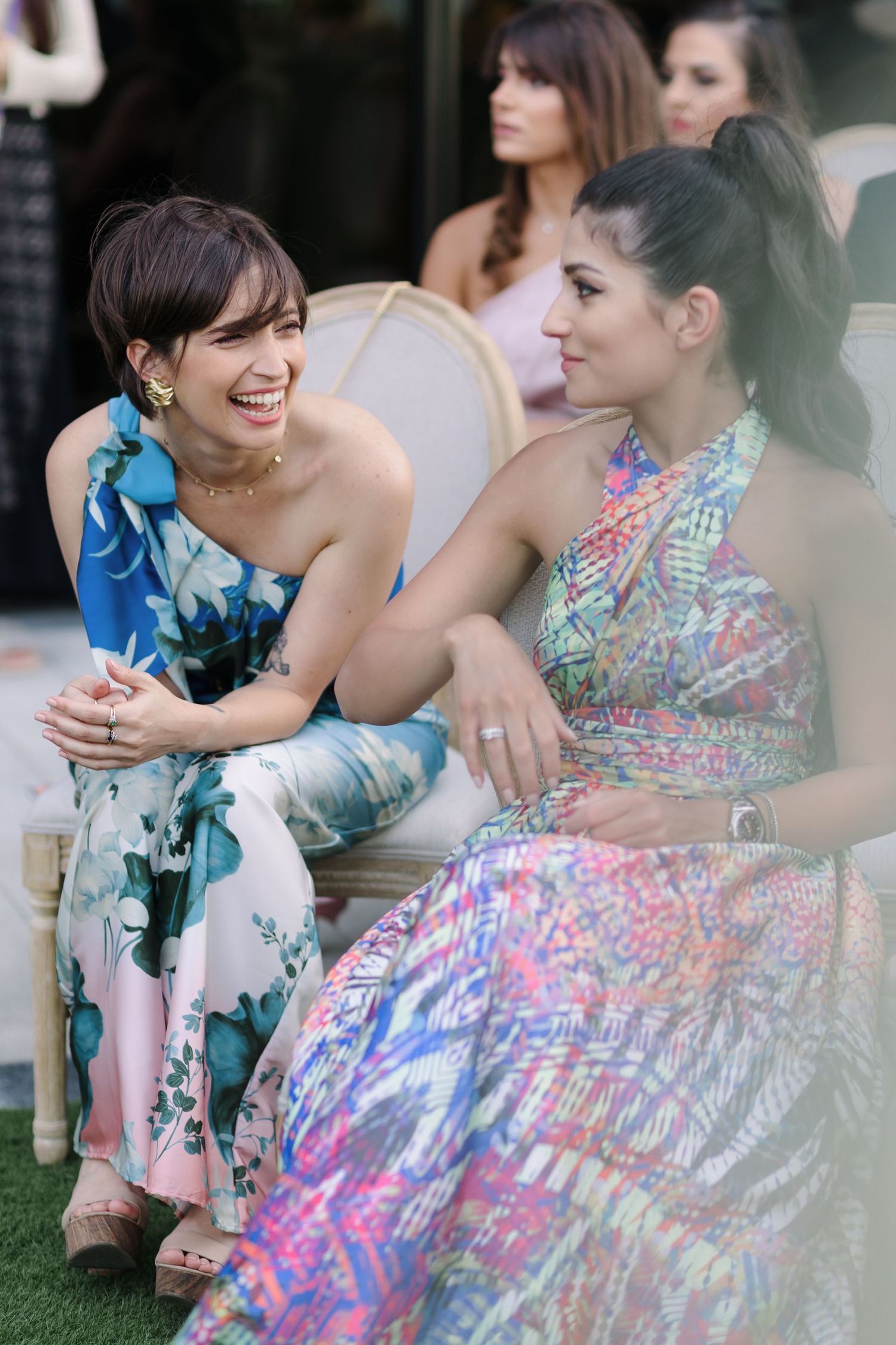 Bridesmaids in colorful floral dresses share joyful moments during wedding celebrations.