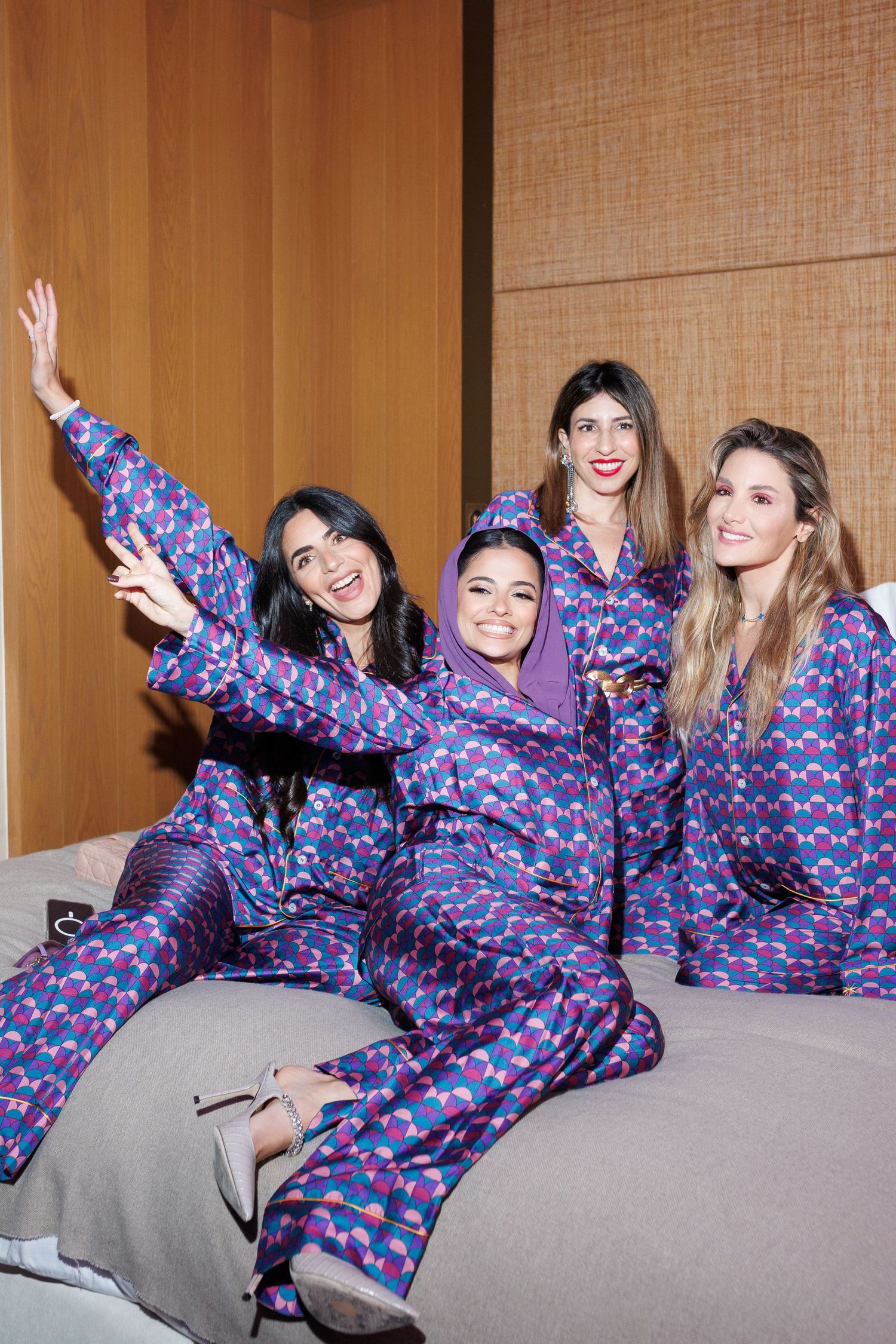 Group wearing matching blue patterned outfits pose playfully on gray couch.