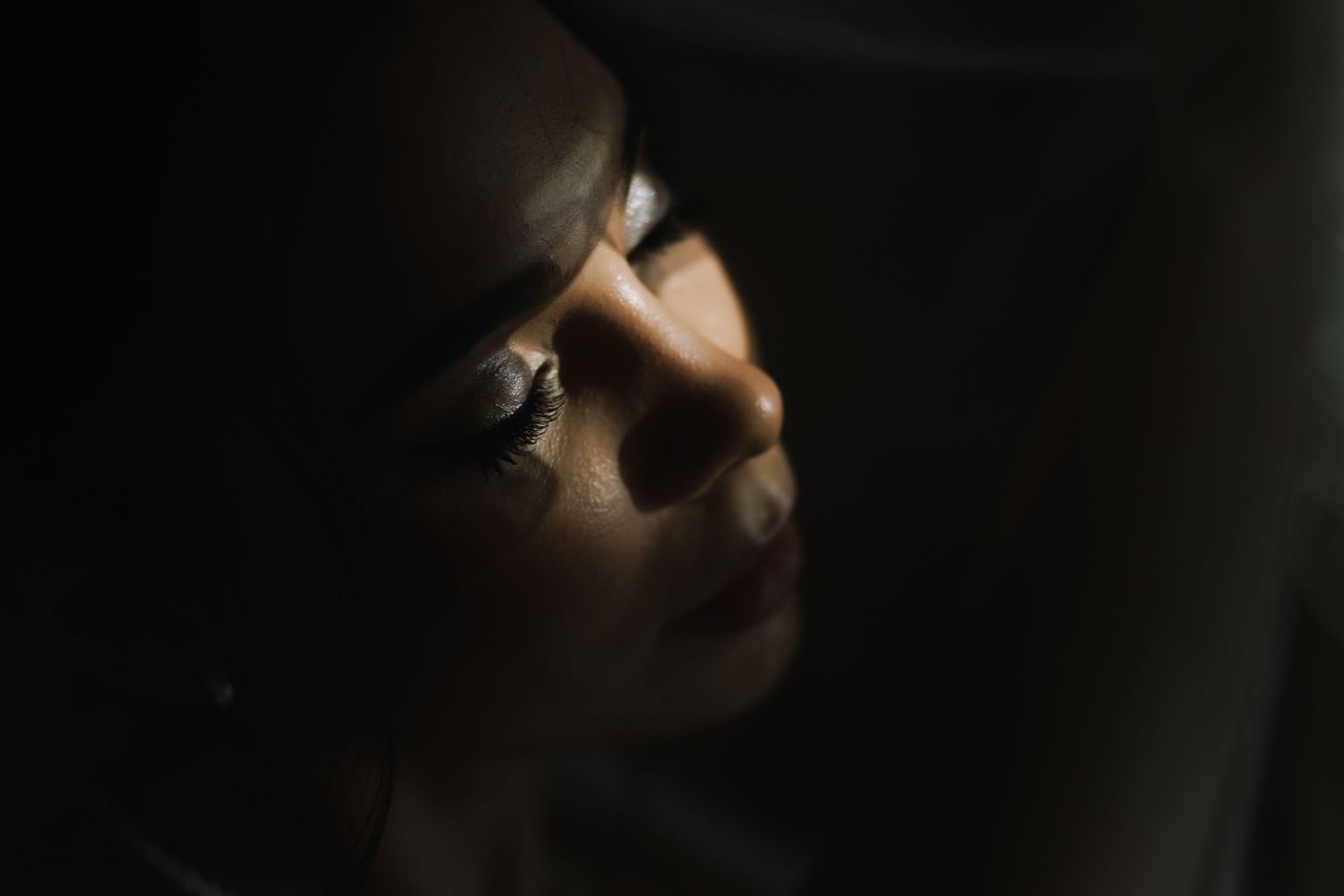 Dramatic low-key portrait with selective lighting creating moody shadows and highlights.