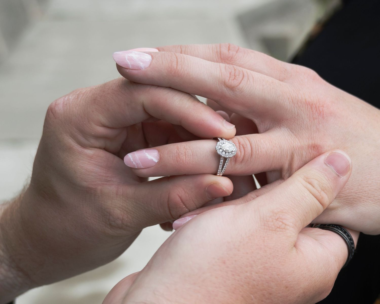 Close-up sequence of placing an engagement ring on a finger.