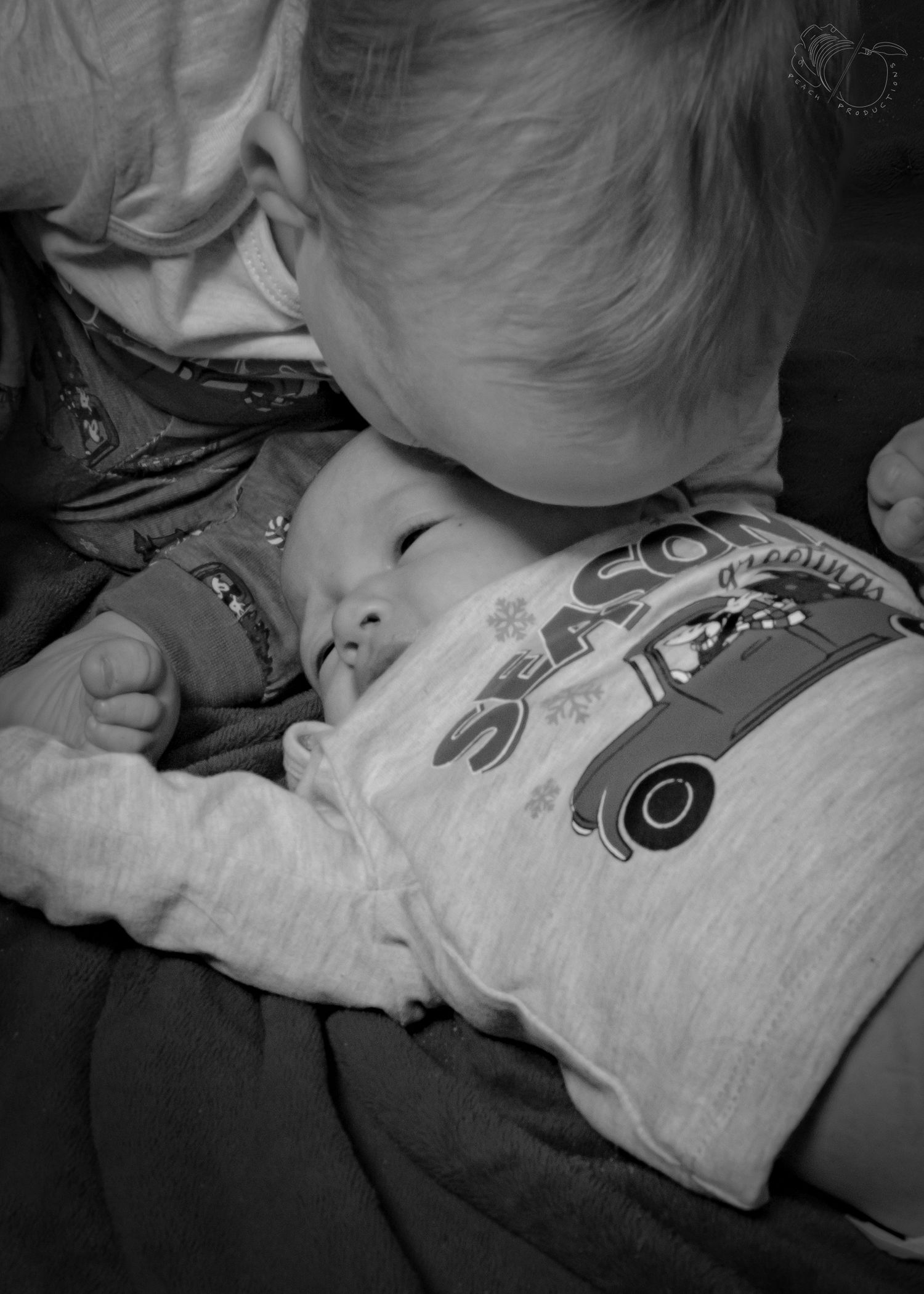 Black and white photo of a baby lying down on a dark surface.