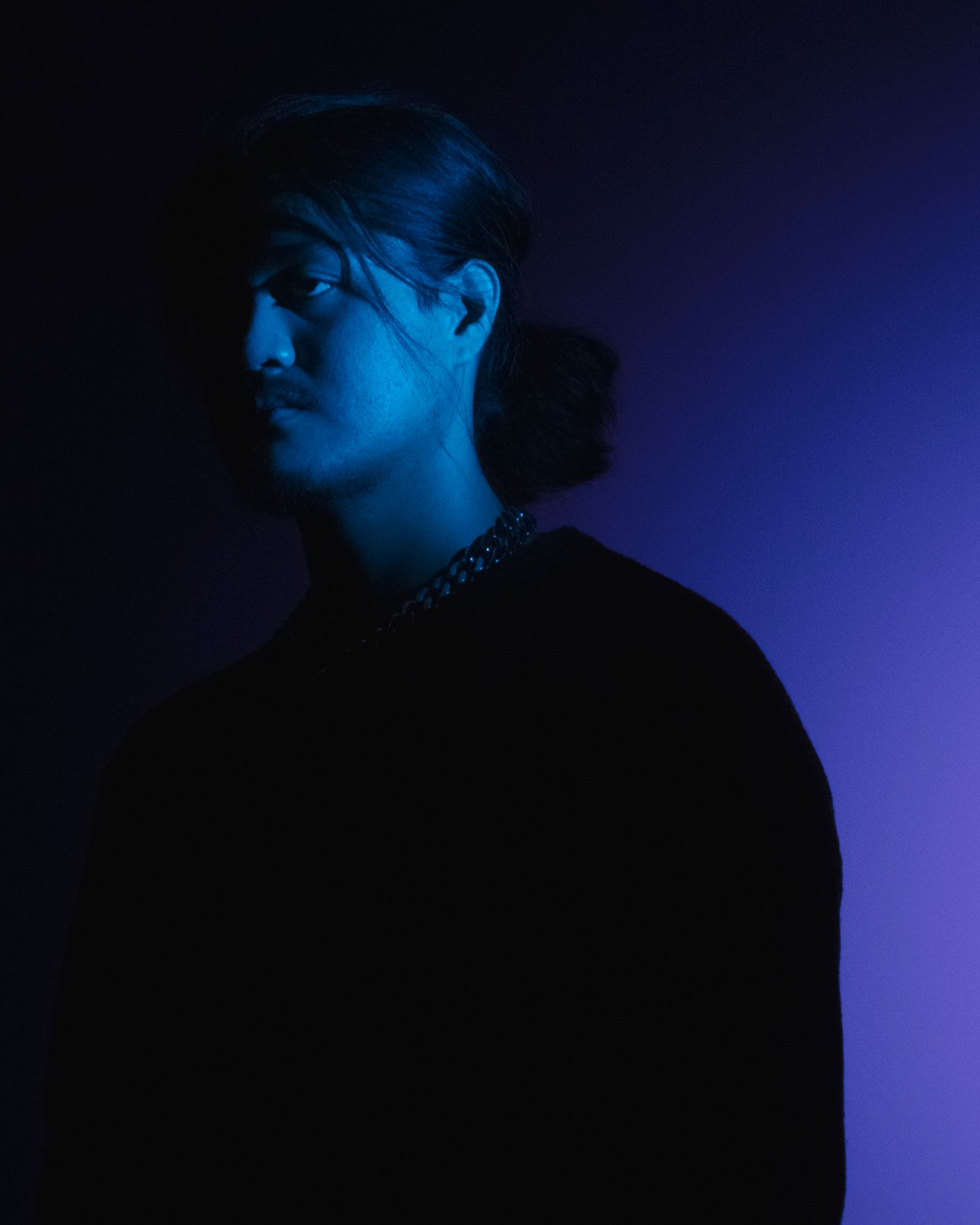 Dramatic silhouette portrait with deep blue lighting and dark shadows.