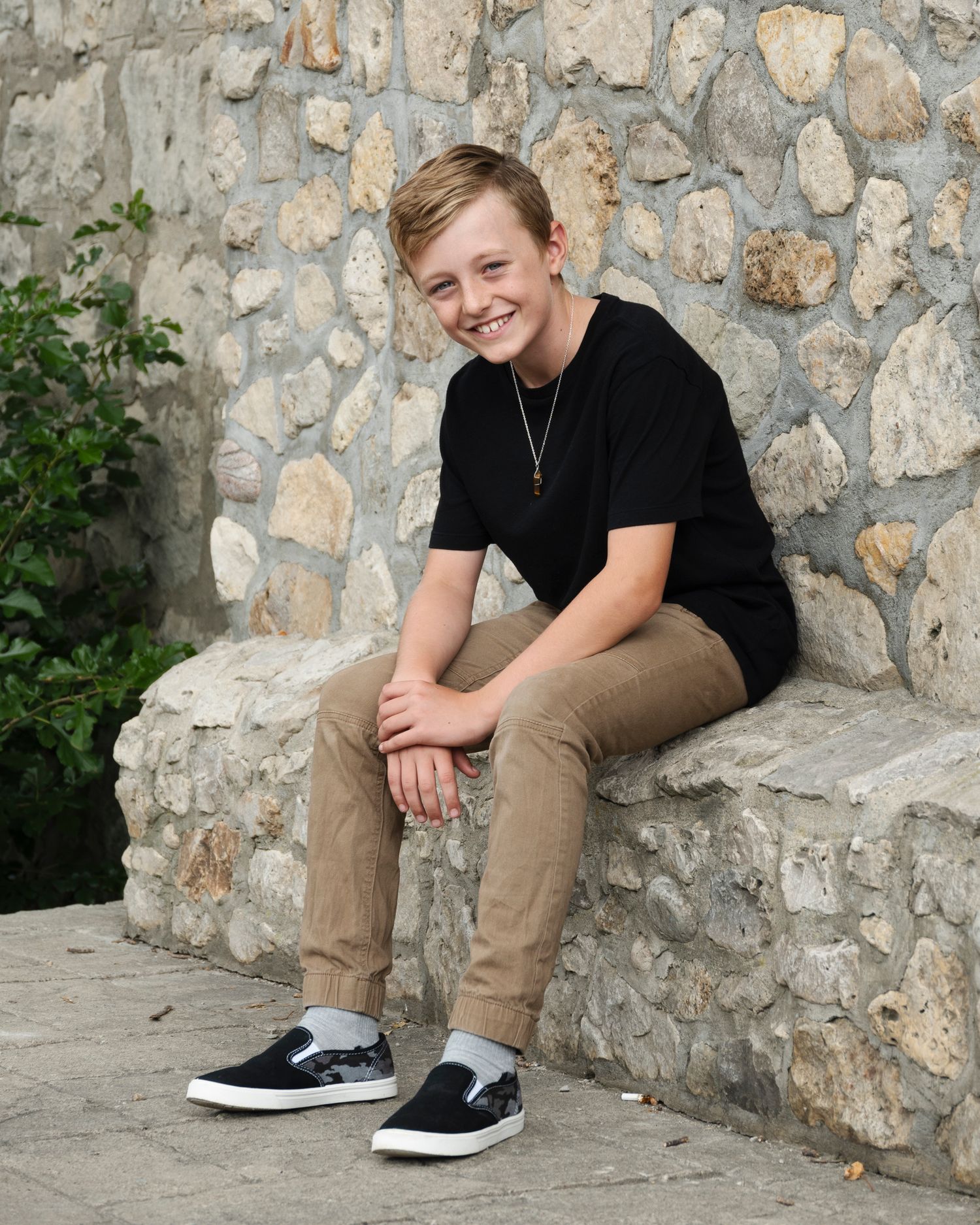 Casual portraits of someone in dark clothing sitting on a stone ledge.